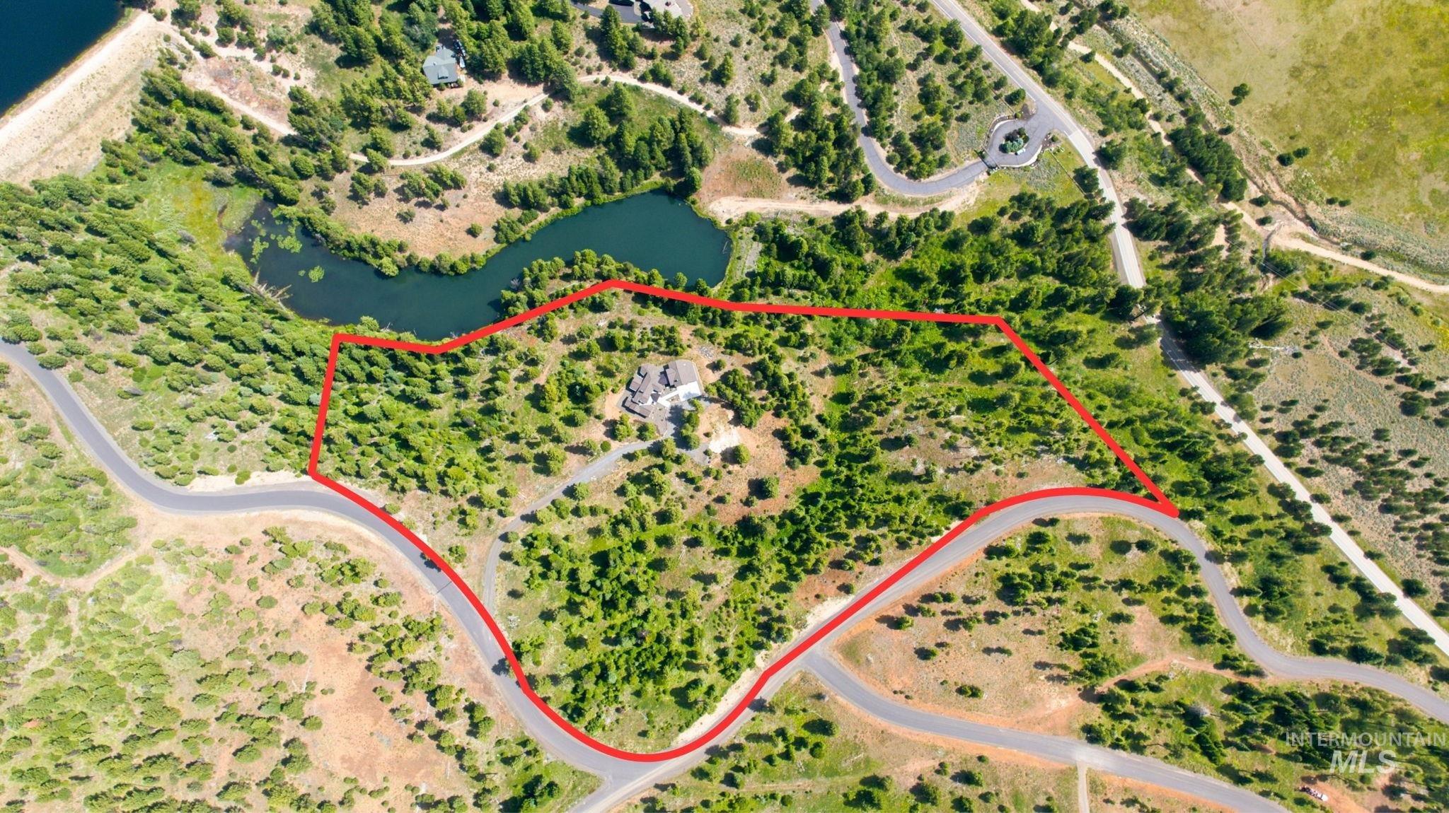 Aerial view of a sprawling property featuring a large residence surrounded by abundant mature trees and natural landscaping