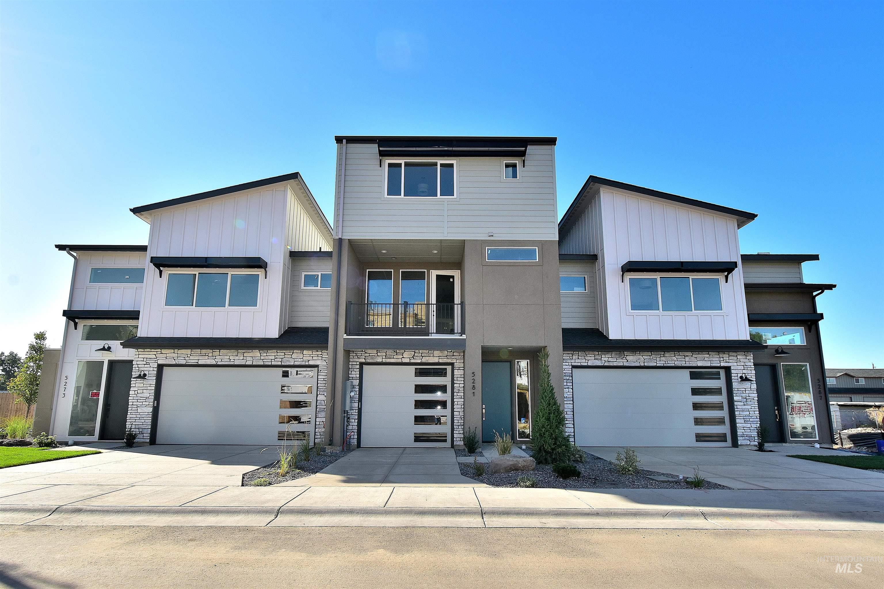 Contemporary house featuring stone siding, a balcony, board and batten siding, and driveway