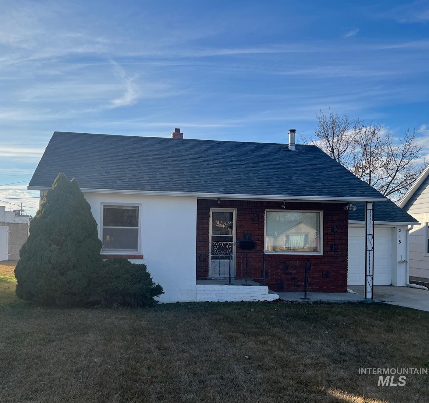 View of front of home with roof with shingles, a front lawn, and brick siding