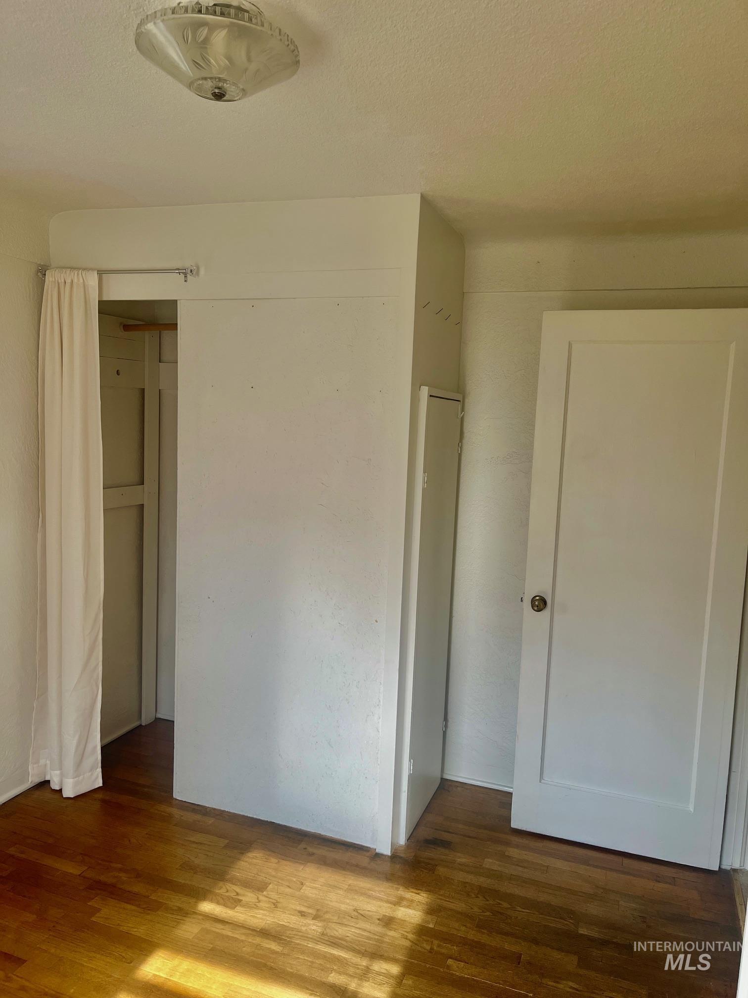 Unfurnished bedroom featuring dark wood-type flooring and a textured ceiling