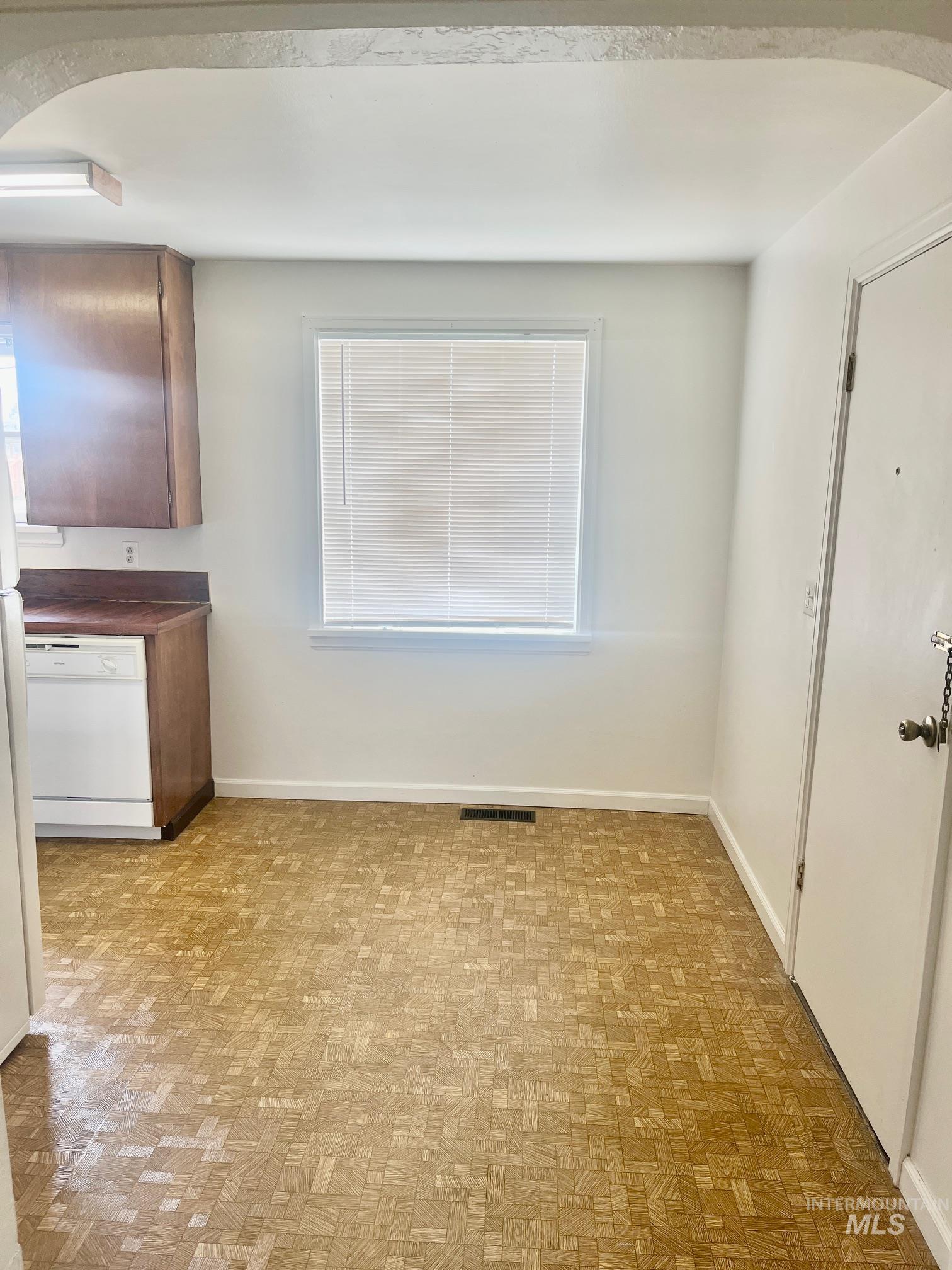Unfurnished dining area featuring arched walkways and light floors