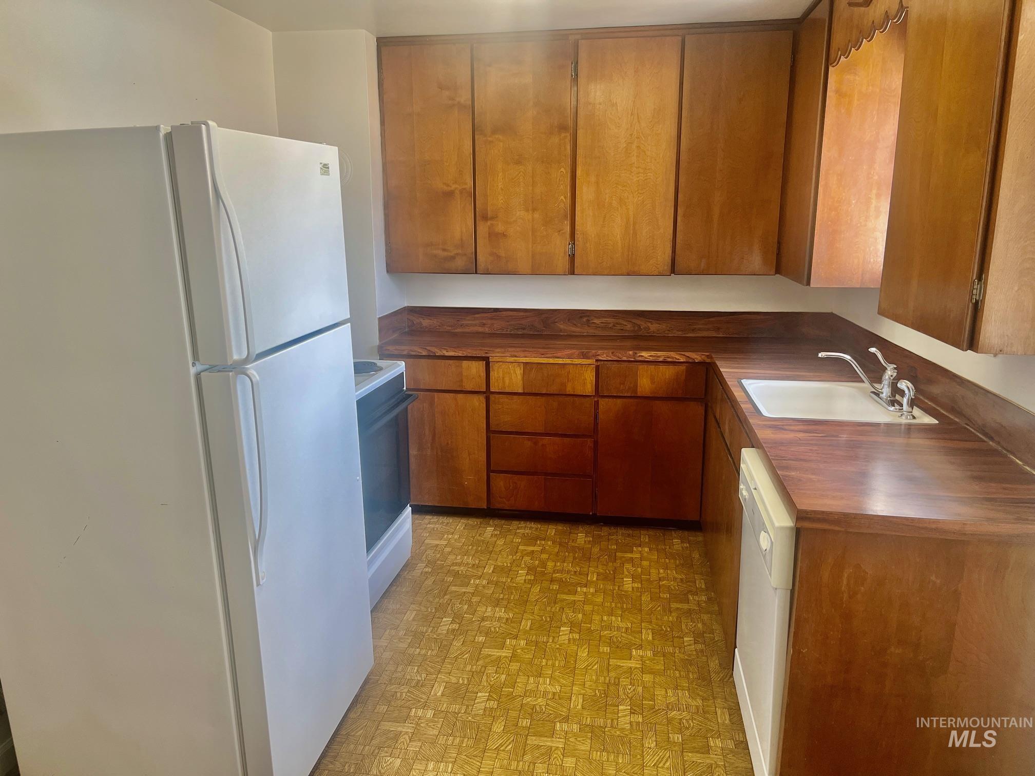 Kitchen with white appliances, dark flooring, and wood finish cabinets