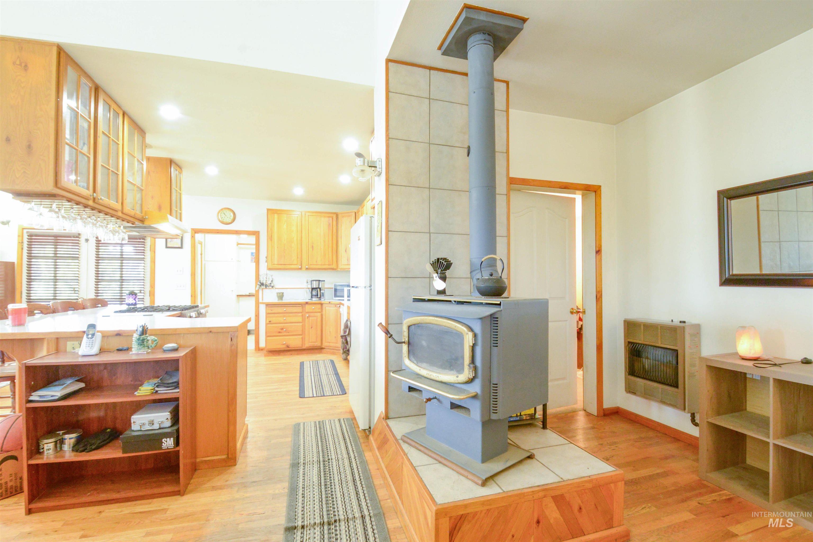 Kitchen featuring open shelves, glass insert cabinets, light wood finished floors, a wood stove, and recessed lighting