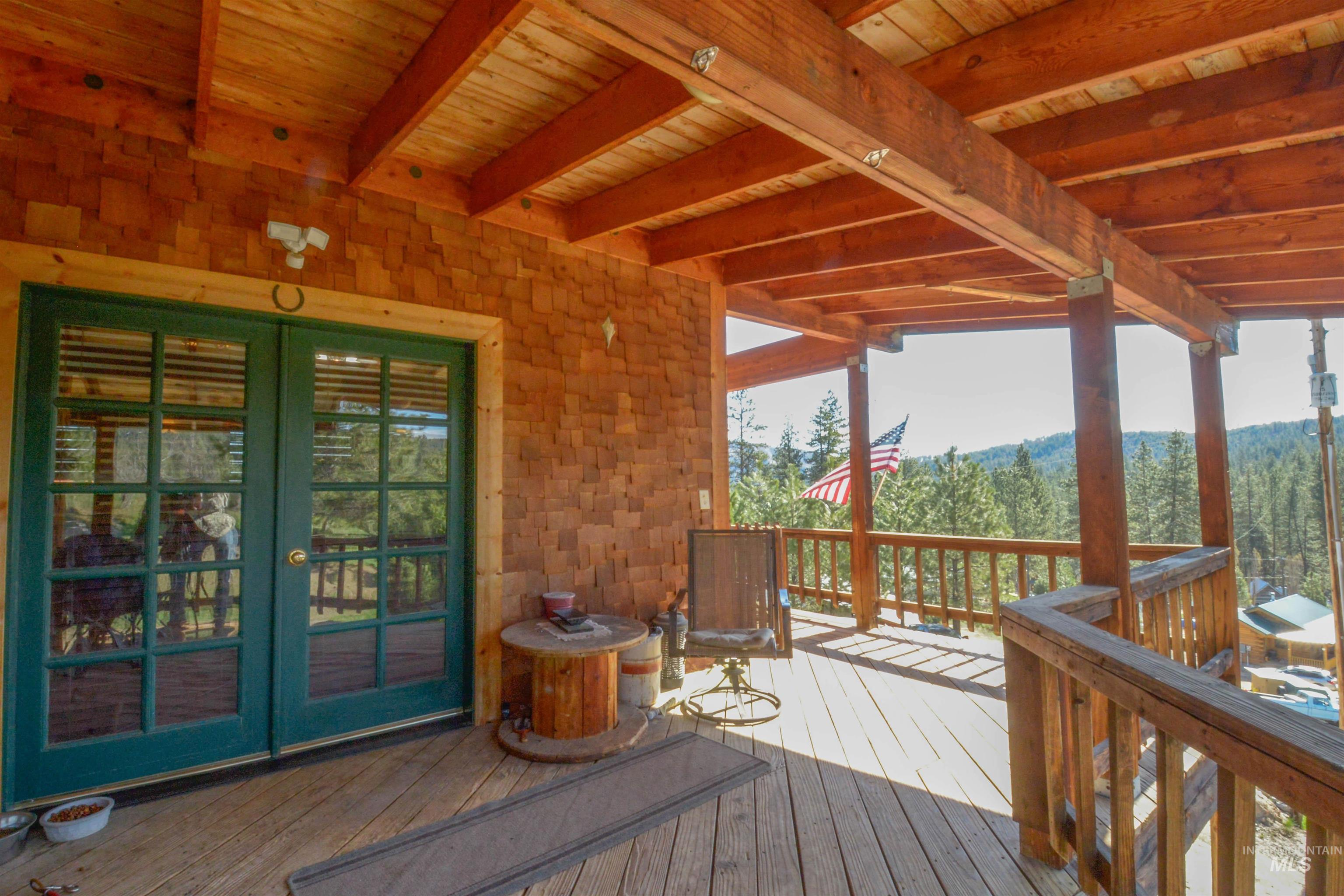 Wooden terrace featuring french doors and a view of trees