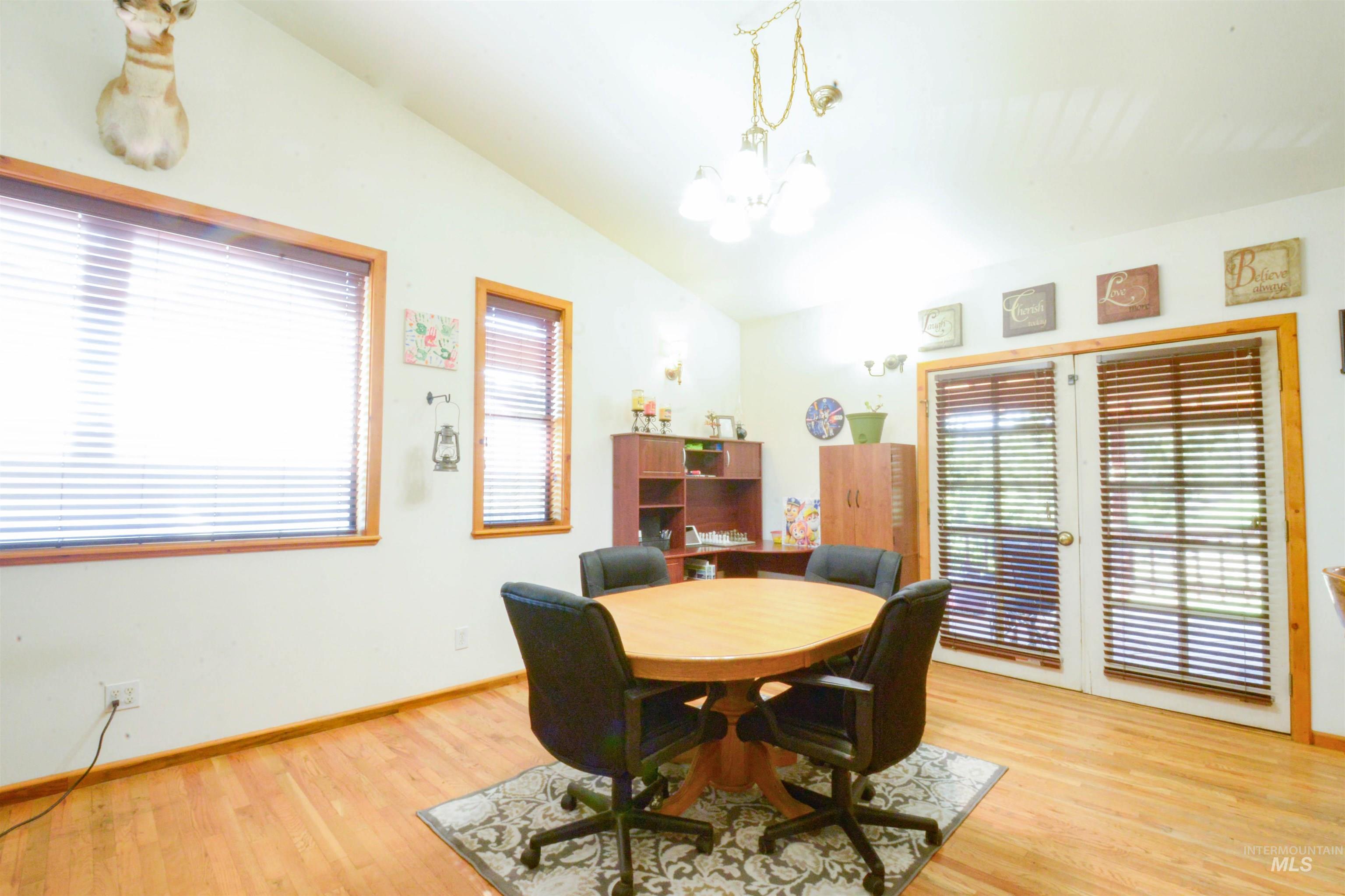 Dining space featuring vaulted ceiling, light wood-style flooring, and a chandelier