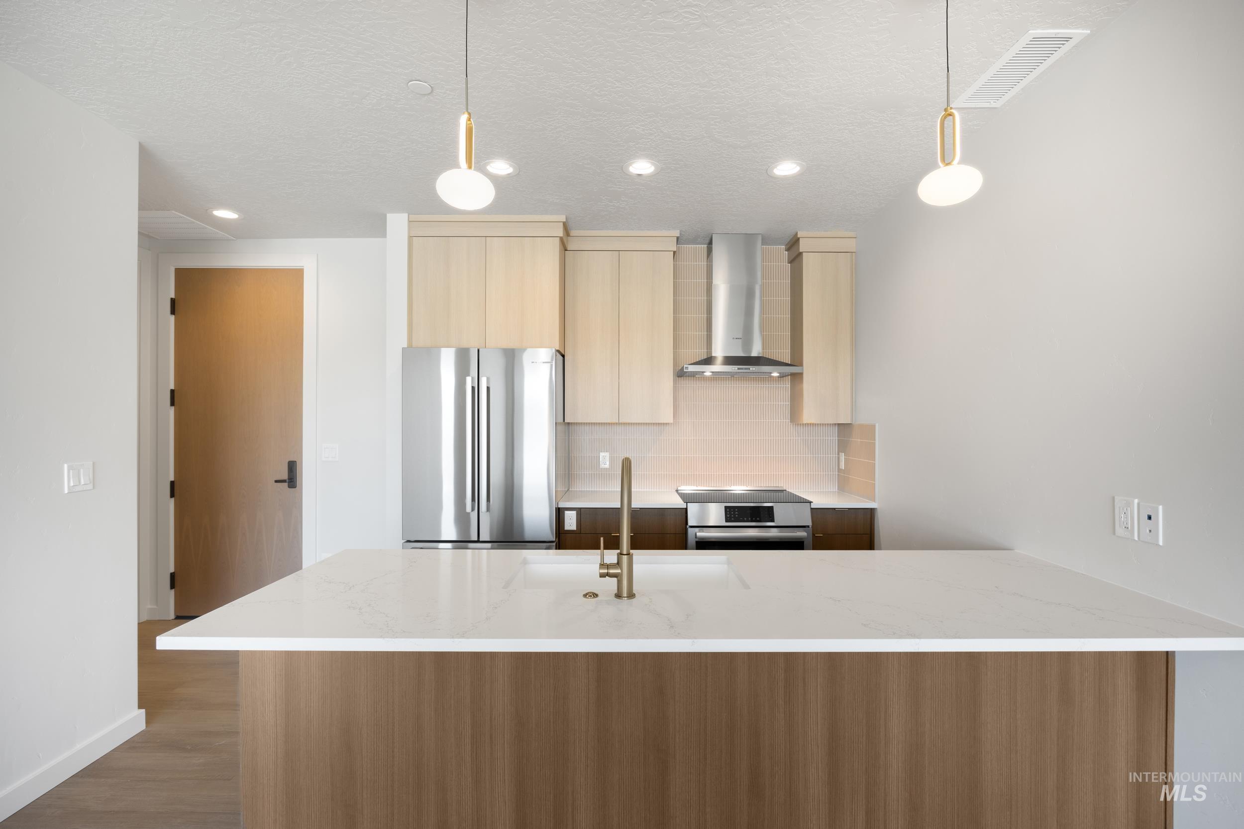 Kitchen featuring a peninsula, appliances with stainless steel finishes, modern cabinets, light stone counters, and backsplash
