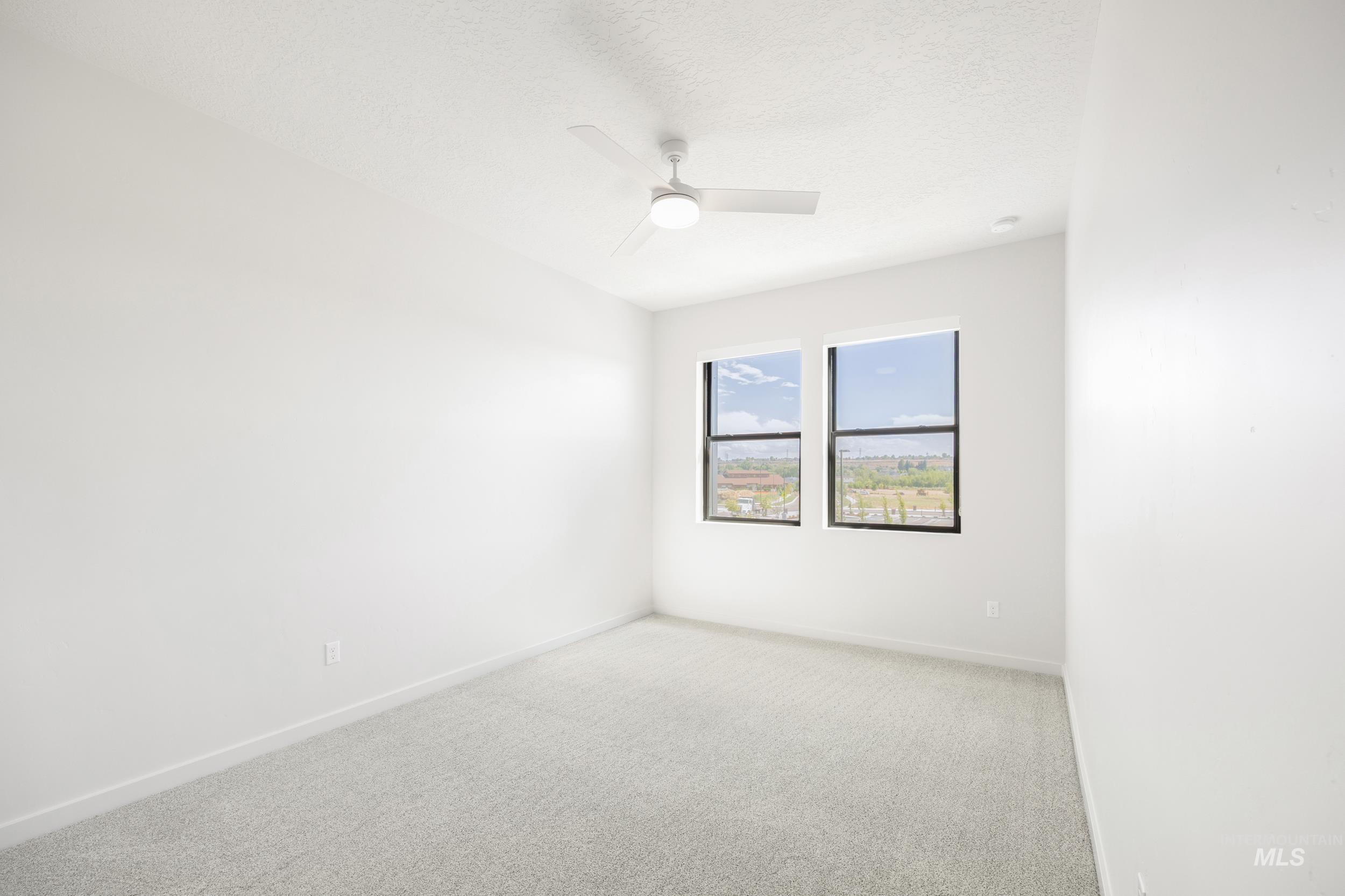 Carpeted spare room with a textured ceiling and a ceiling fan