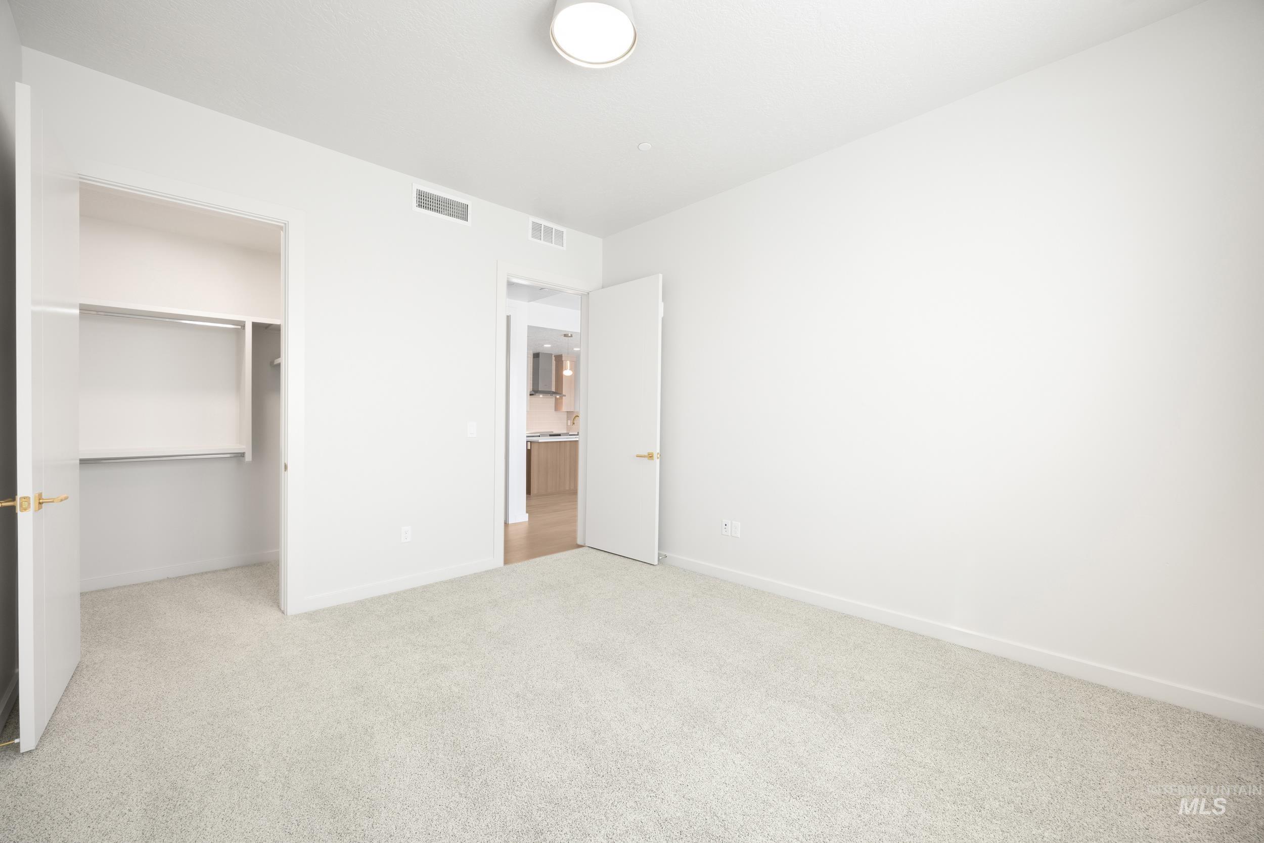 Unfurnished bedroom with carpet and a walk in closet