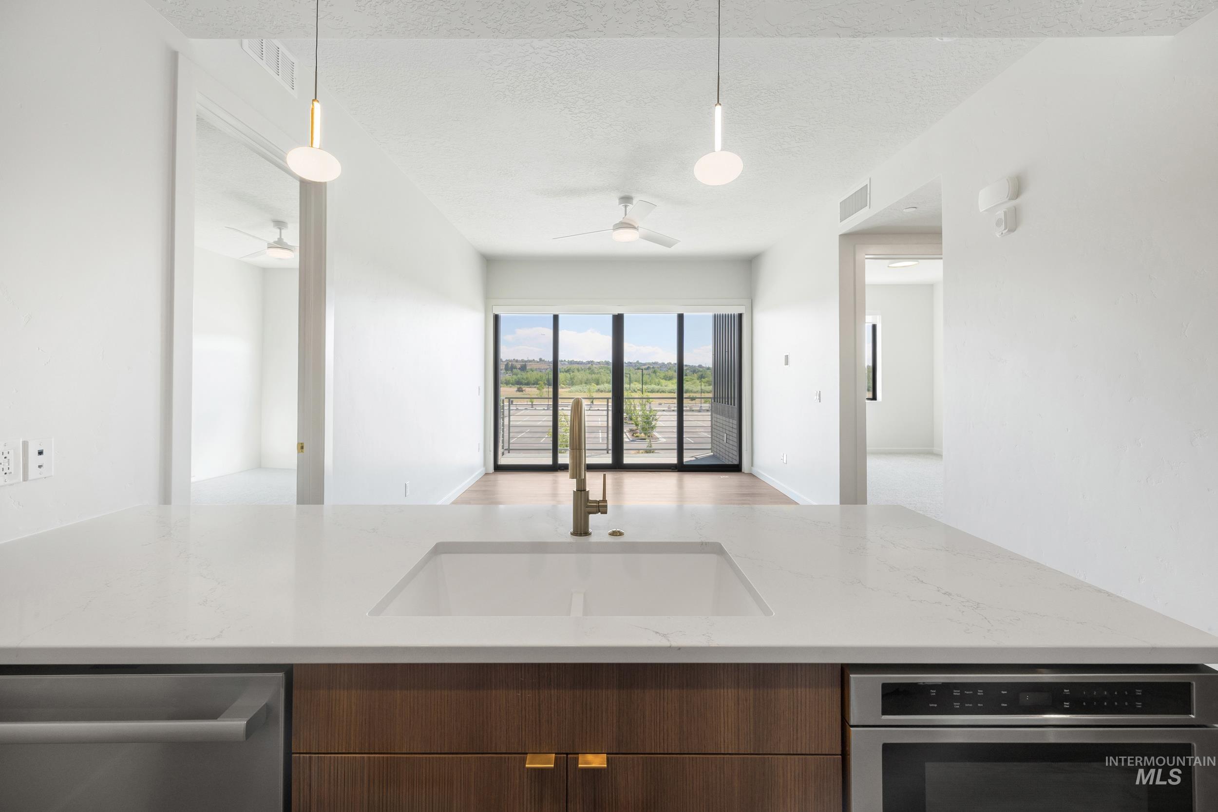 Kitchen with modern cabinets, light stone countertops, open floor plan, pendant lighting, and stainless steel appliances