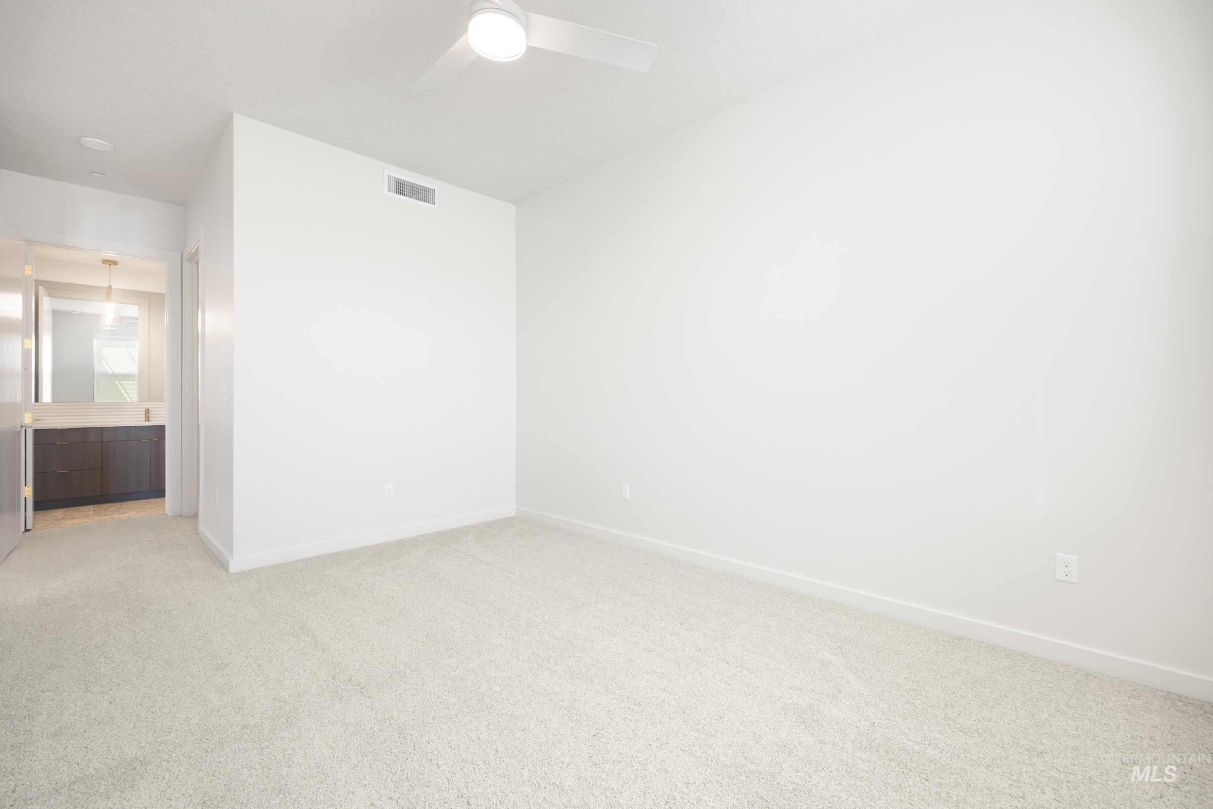 Unfurnished bedroom featuring carpet flooring, a ceiling fan, and ensuite bathroom