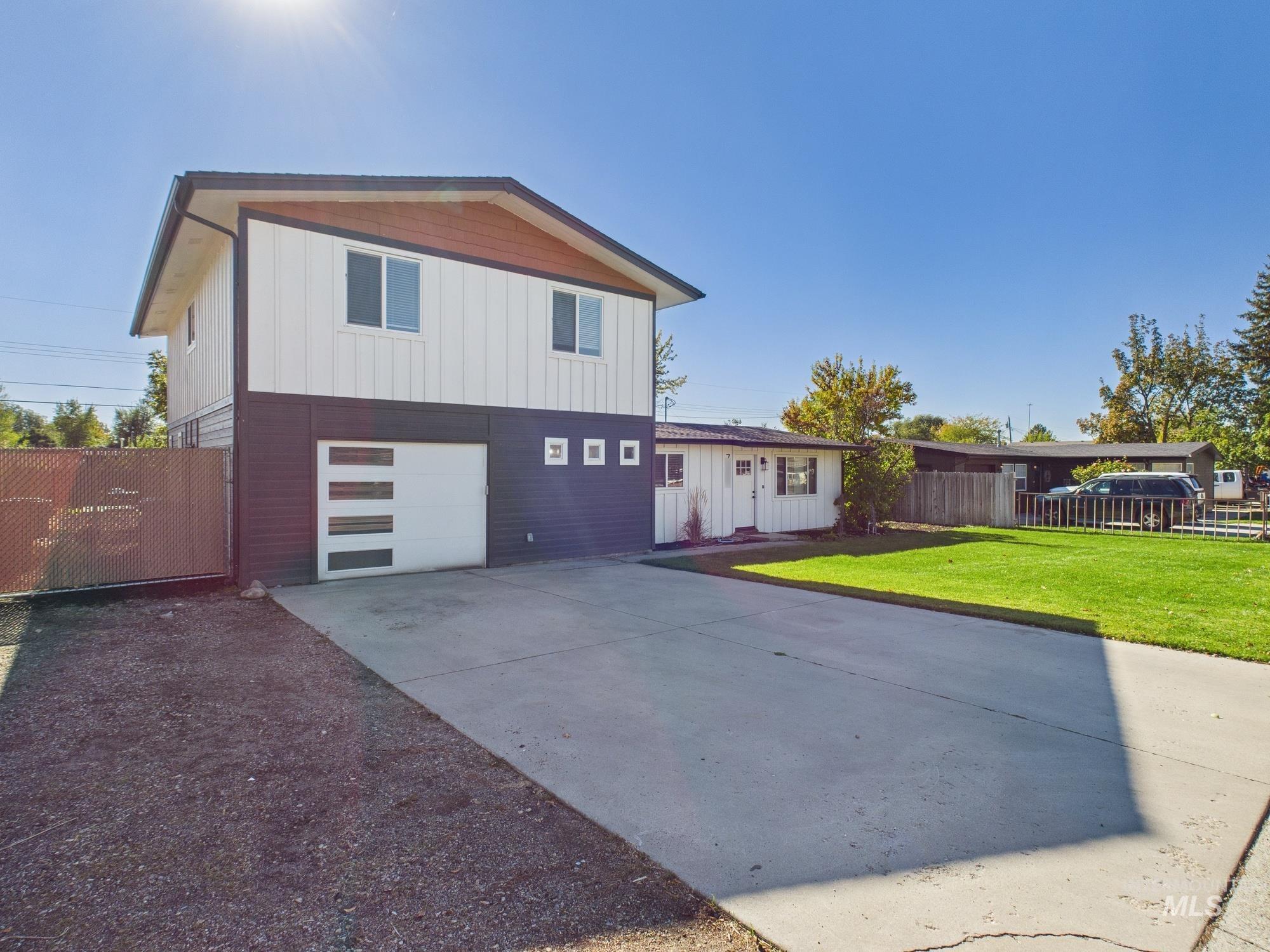 View of front of property with concrete driveway, board and batten siding, and an attached garage