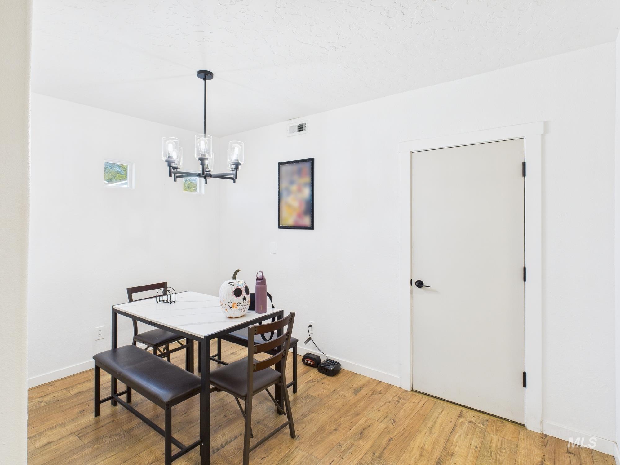 Dining area featuring light wood-style flooring, a chandelier, and a textured ceiling