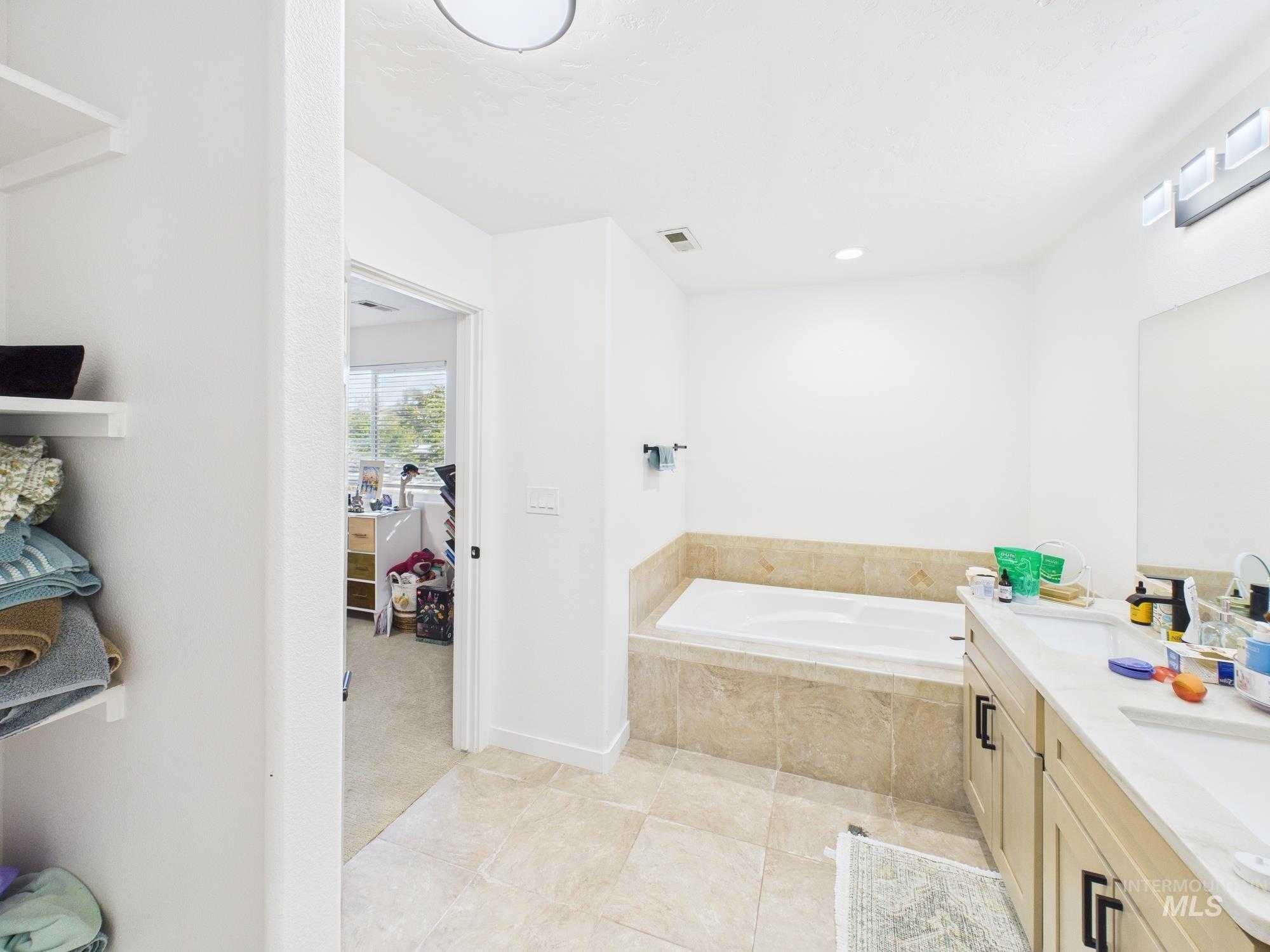 Full bathroom featuring double vanity, a bath, and light tile patterned floors