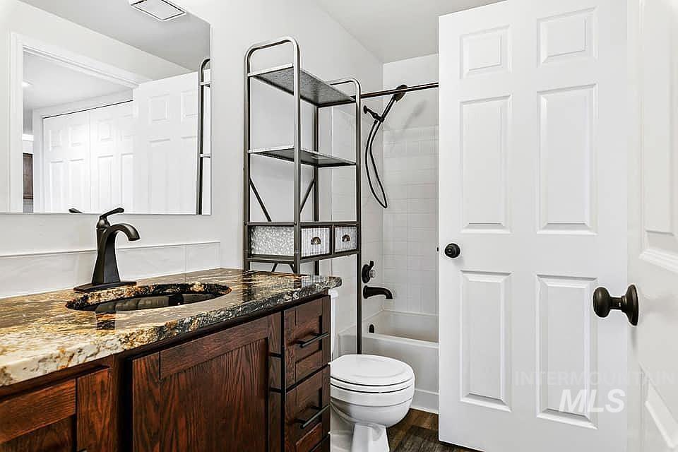 Full bathroom with vanity, shower / bathtub combination, and dark wood-style flooring