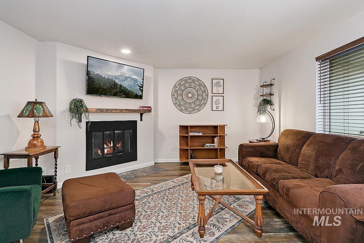 Living area featuring a glass covered fireplace, wood finished floors, and recessed lighting
