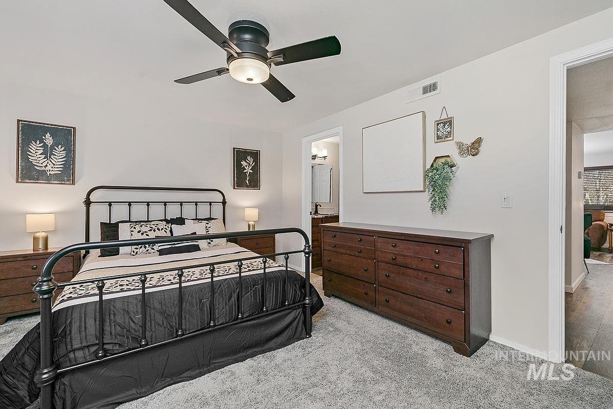 Bedroom with light colored carpet, a ceiling fan, and connected bathroom
