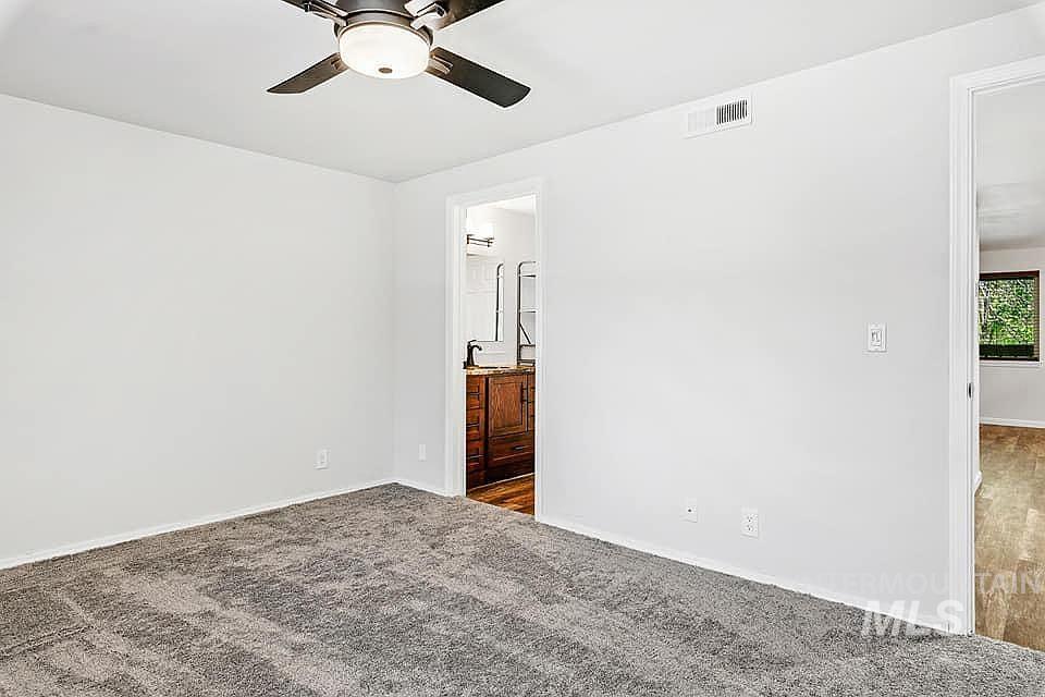 Unfurnished bedroom featuring carpet, a ceiling fan, and connected bathroom