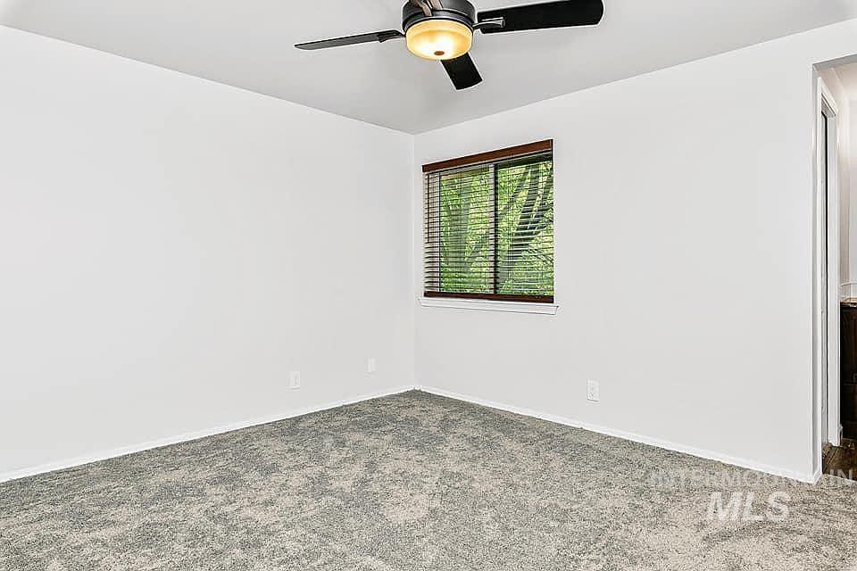Carpeted spare room with baseboards and a ceiling fan