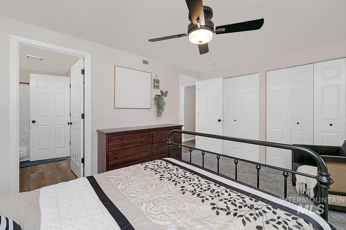 Bedroom featuring two closets, a ceiling fan, and dark wood-type flooring