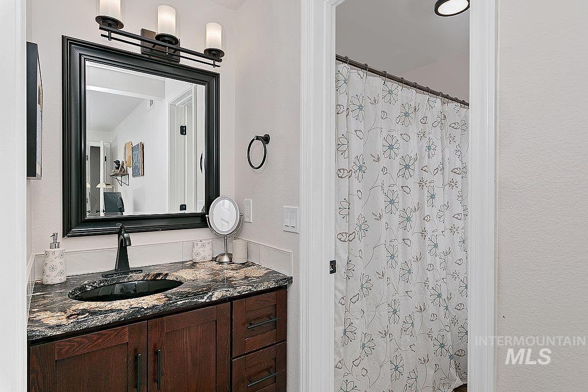 Bathroom featuring vanity, curtained shower, and a textured wall