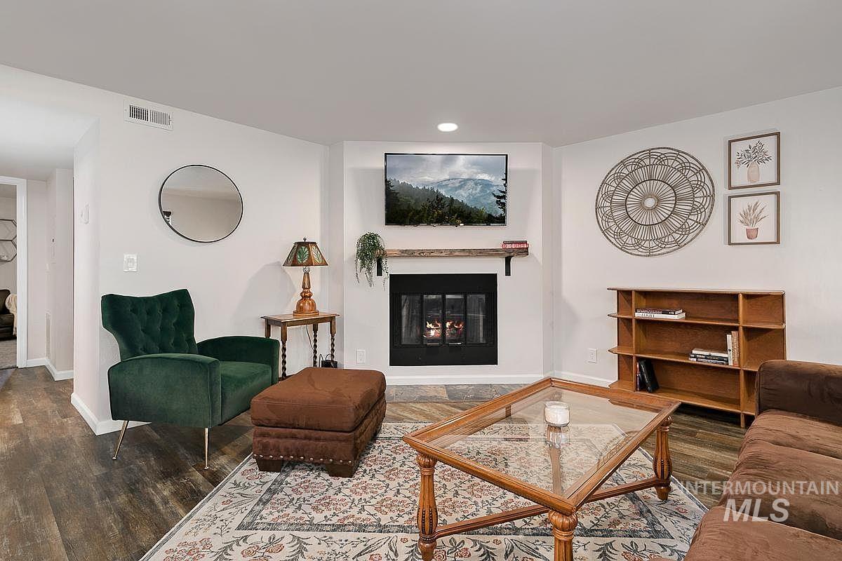 Living area featuring dark wood-style floors, a glass covered fireplace, and recessed lighting
