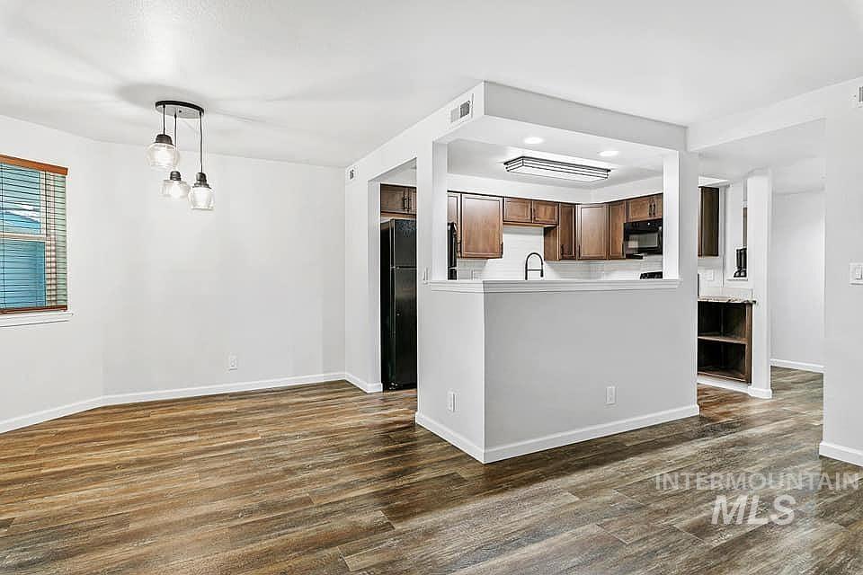 Kitchen with dark wood-style floors, black appliances, light countertops, hanging light fixtures, and recessed lighting