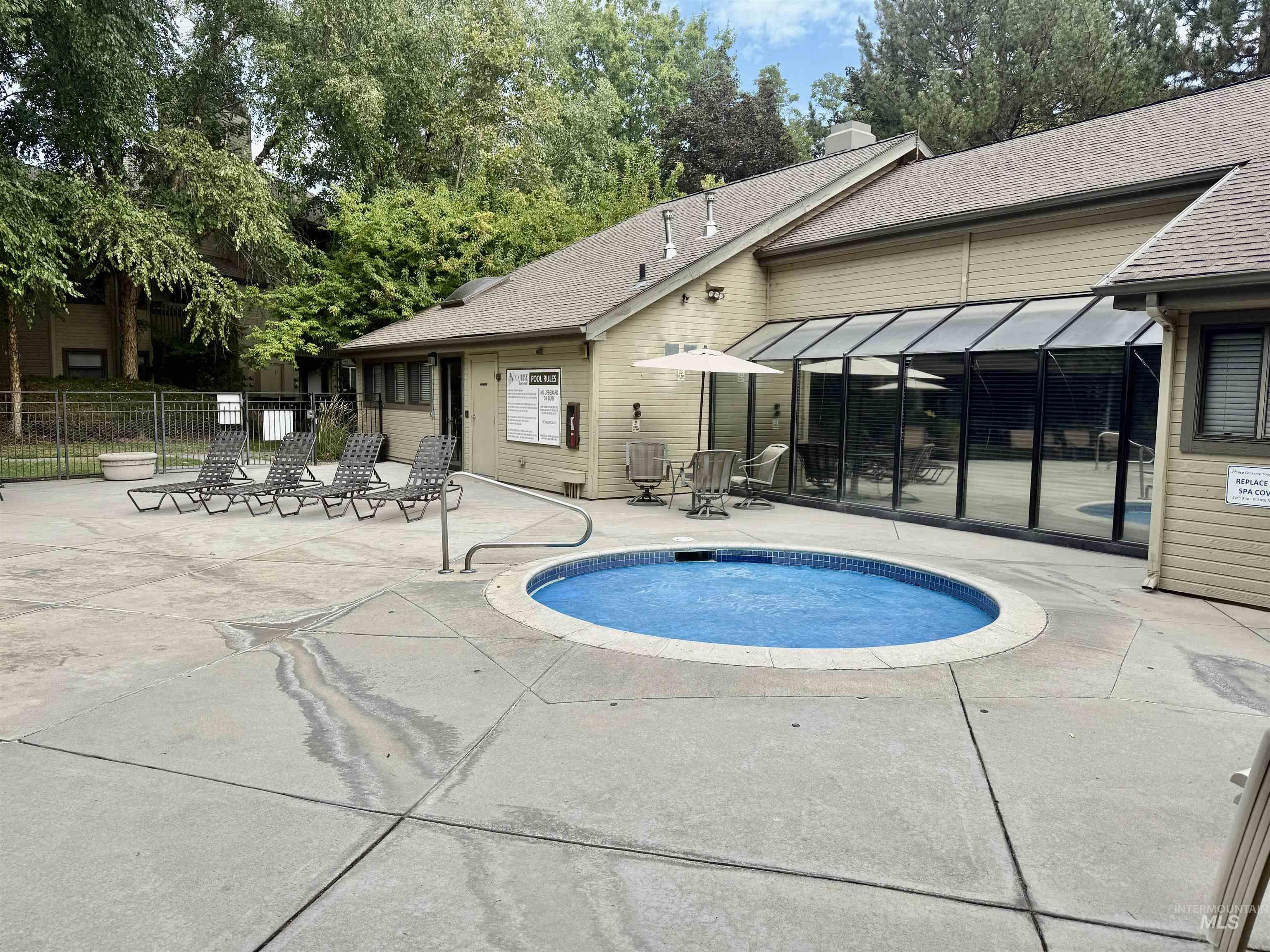 View of swimming pool featuring a patio, a community hot tub, a pool, and a sunroom