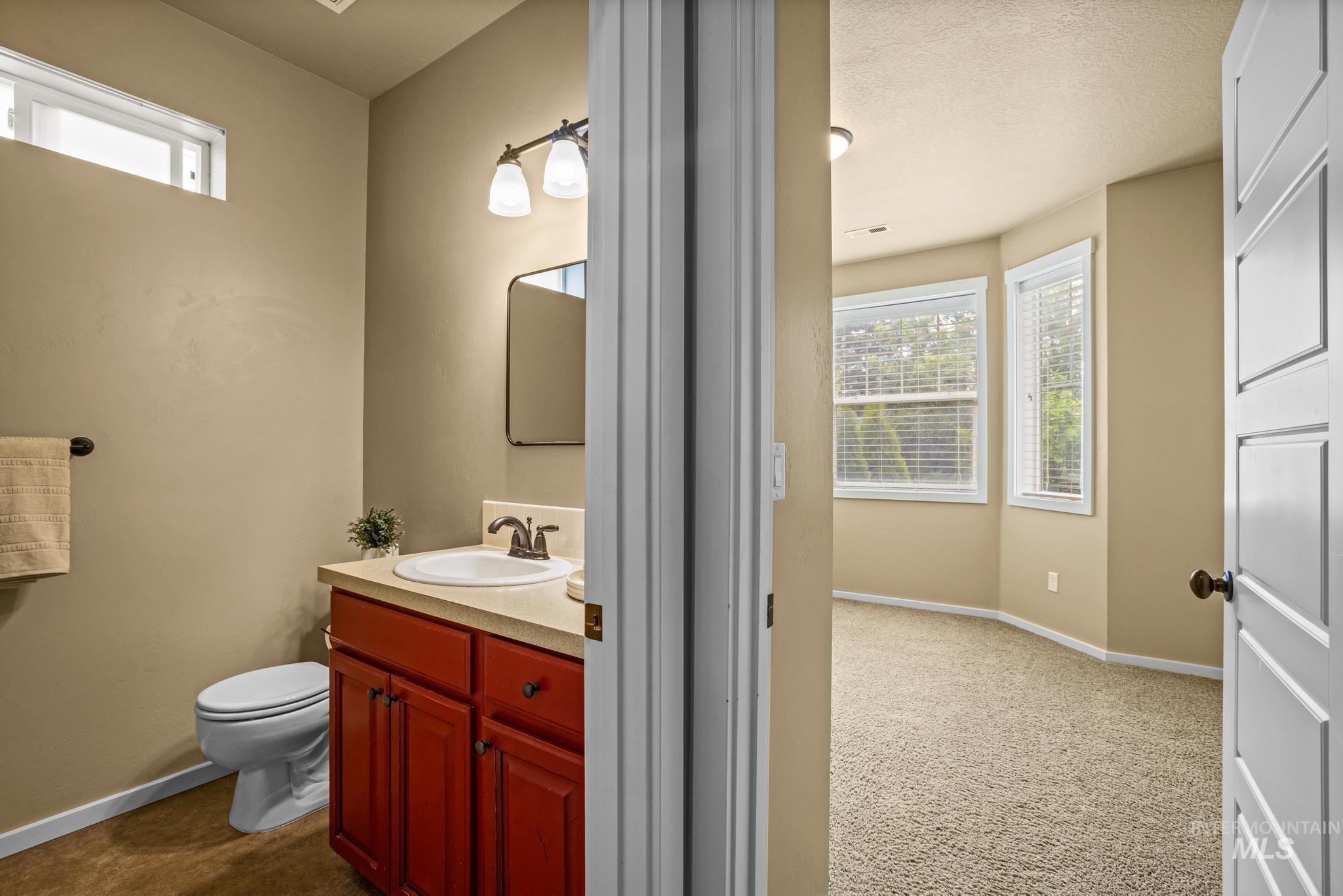 Bathroom featuring a red wood-finish vanity with a drop-in sink and light-toned countertop