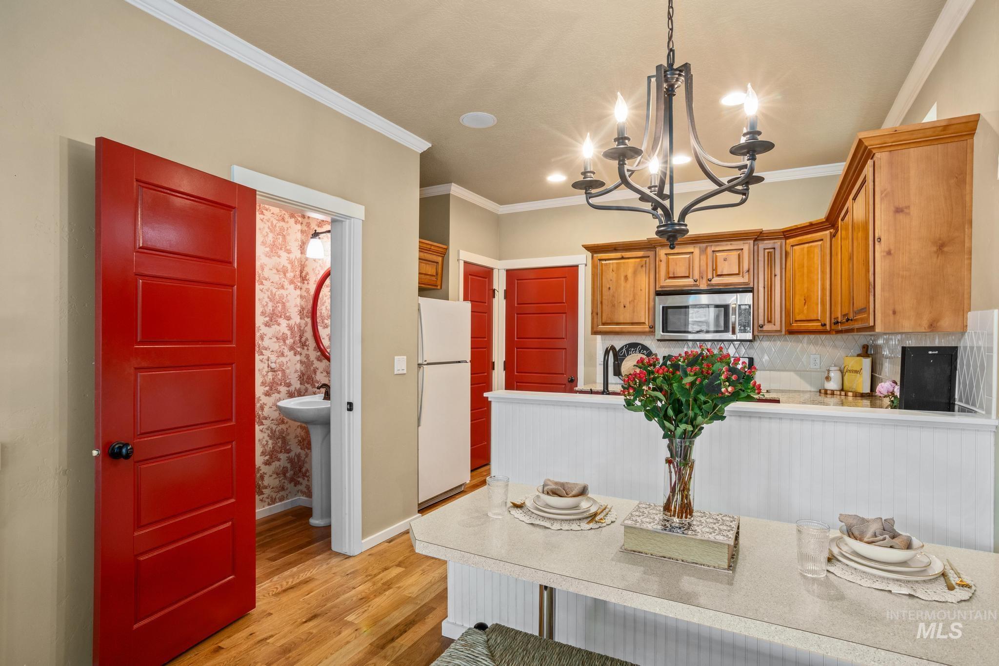 Open-concept living space featuring wood-finish flooring, a kitchen with natural wood cabinetry, a stainless steel microwave, and white subway tile backsplash