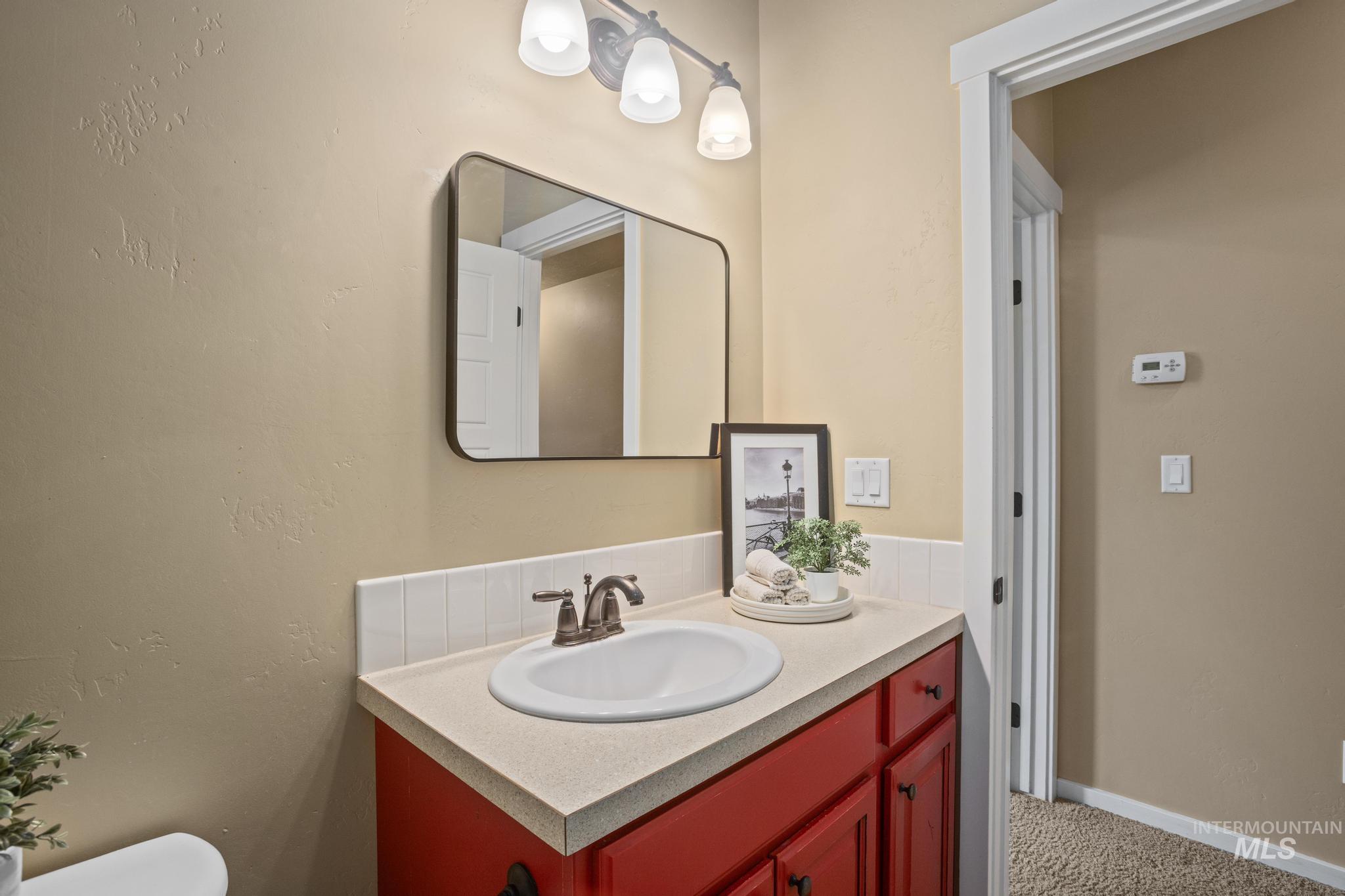 Bathroom vanity featuring a red cabinet base, white integrated sink, and bronze-finish faucet