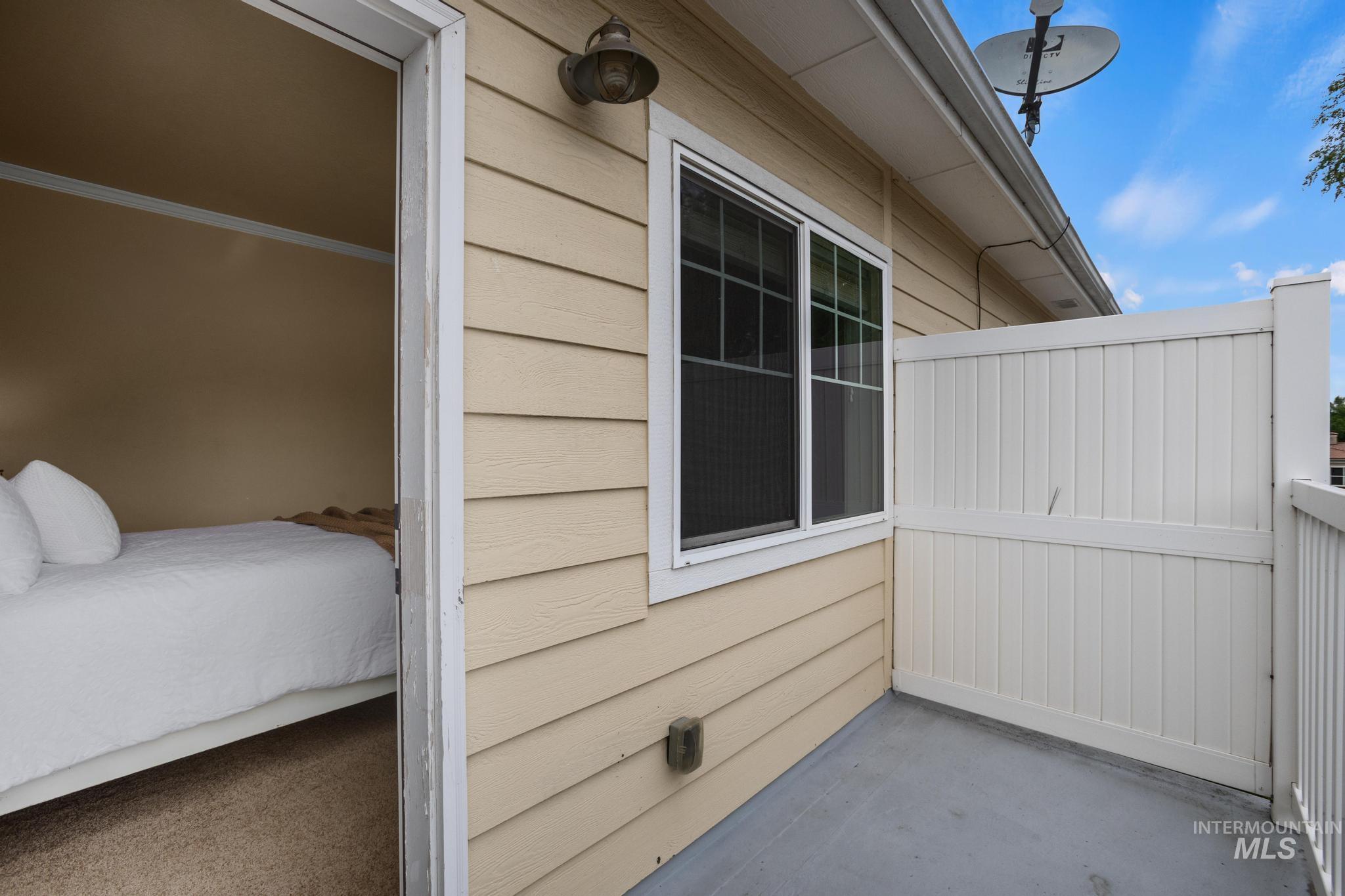 Private outdoor patio space featuring white panel fencing and a painted concrete surface