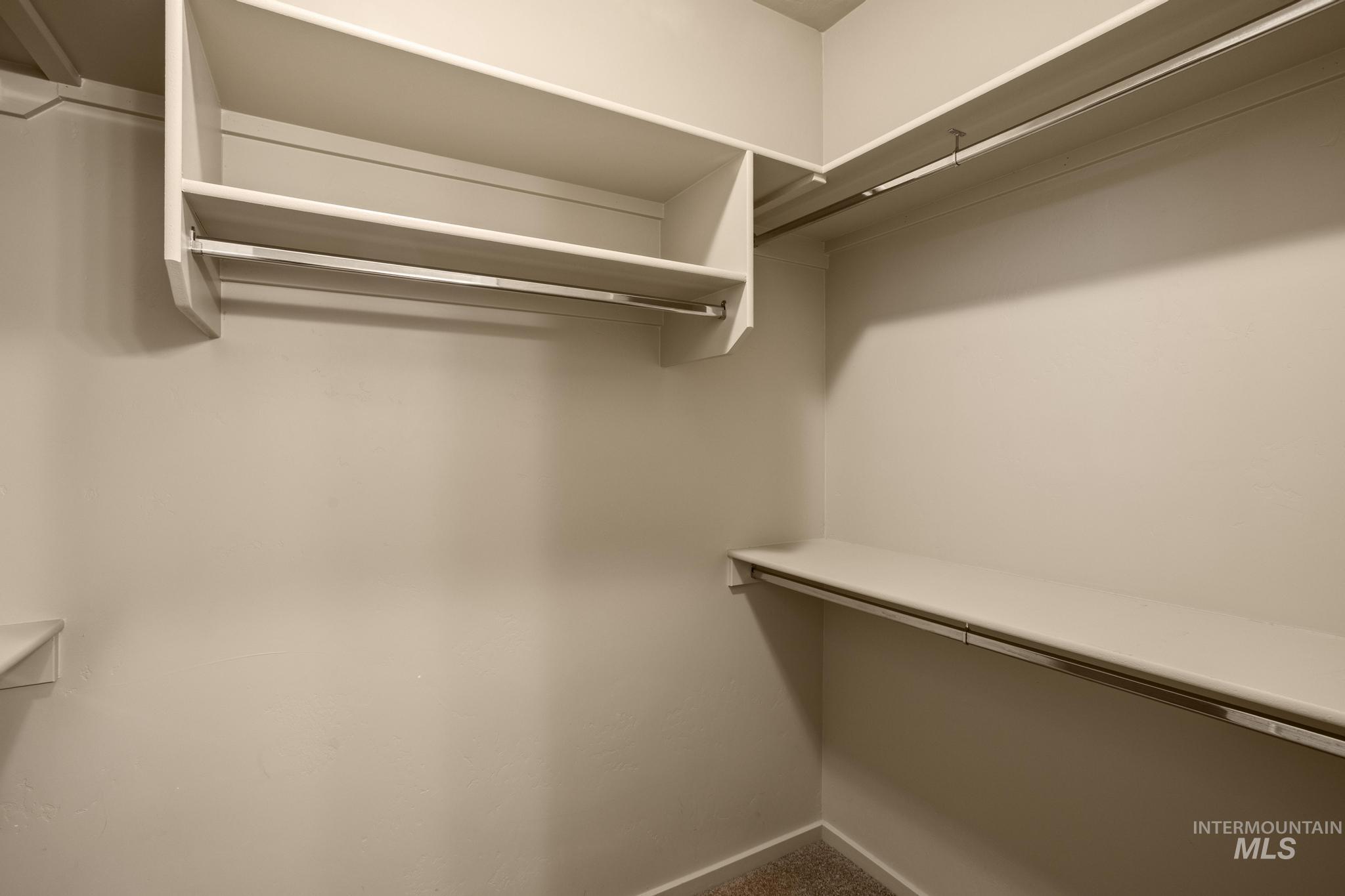 Walk-in closet with built-in shelving, multiple hanging rods, and neutral wall tones