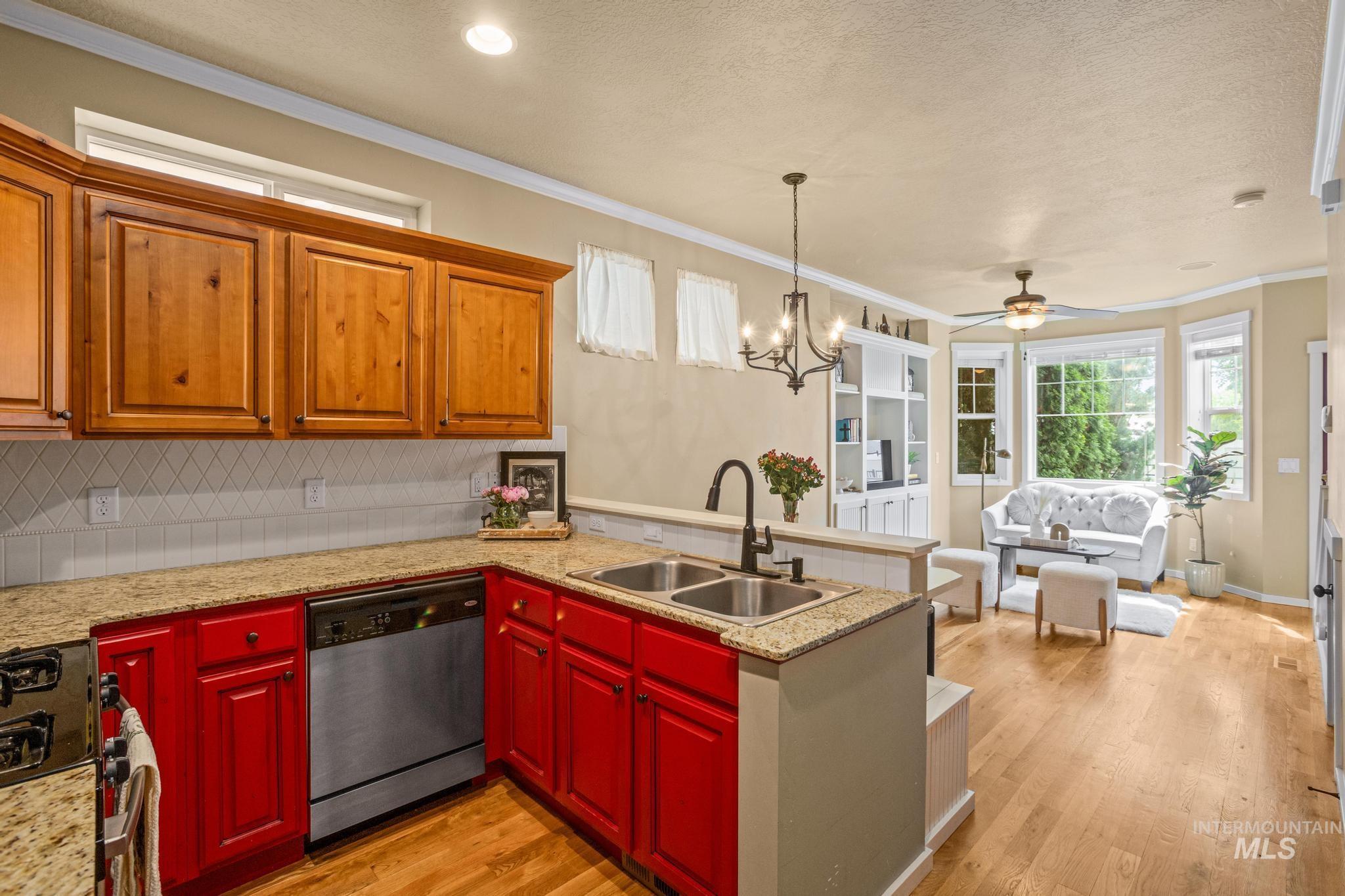 Open-concept living space featuring a kitchen with red lower cabinetry, wood upper cabinetry, and granite countertops