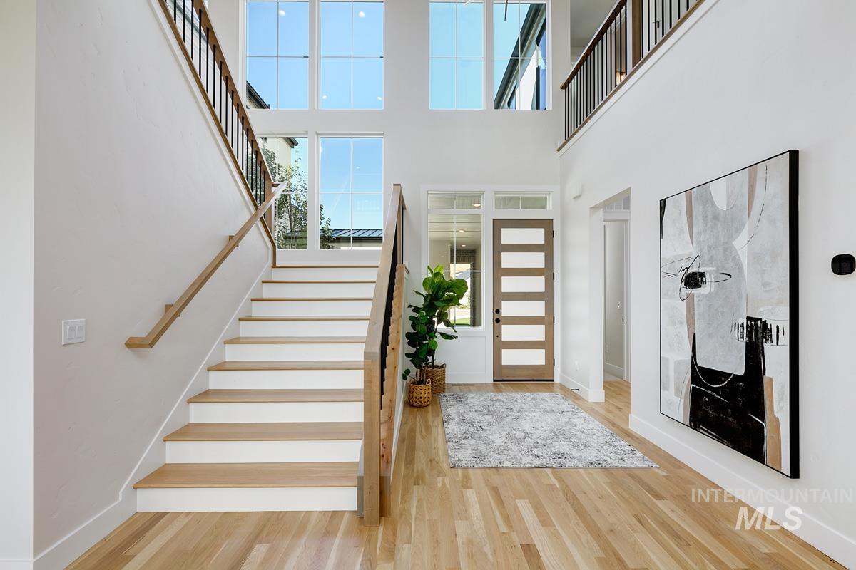 Foyer featuring stairs, light wood-style floors, and a high ceiling
