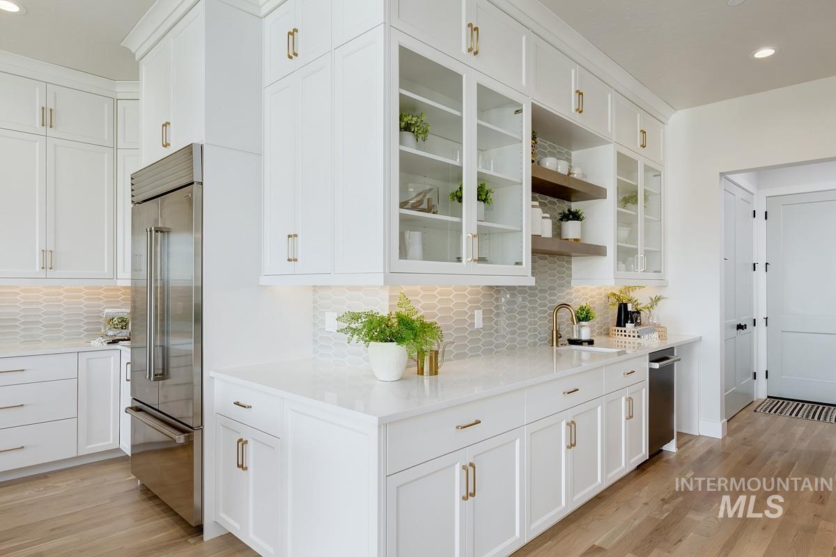 Kitchen featuring glass insert cabinets, open shelves, recessed lighting, built in refrigerator, and white cabinets