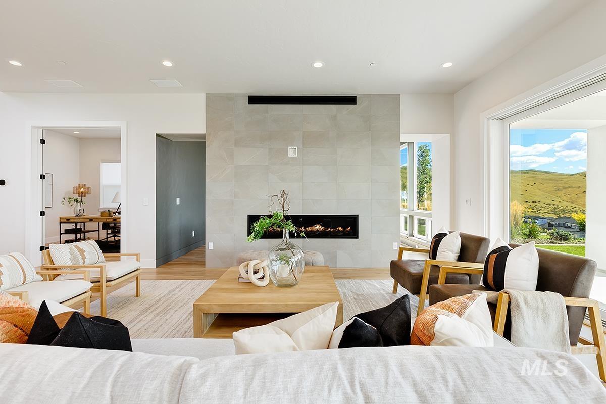 Living area with a tiled fireplace, recessed lighting, and wood finished floors