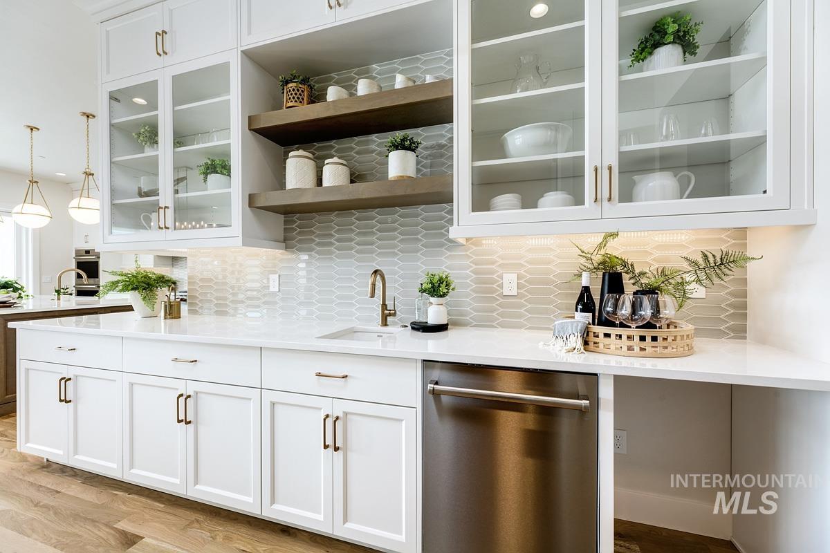 Bar area featuring white cabinetry, stainless steel appliances, backsplash, and hanging light fixtures