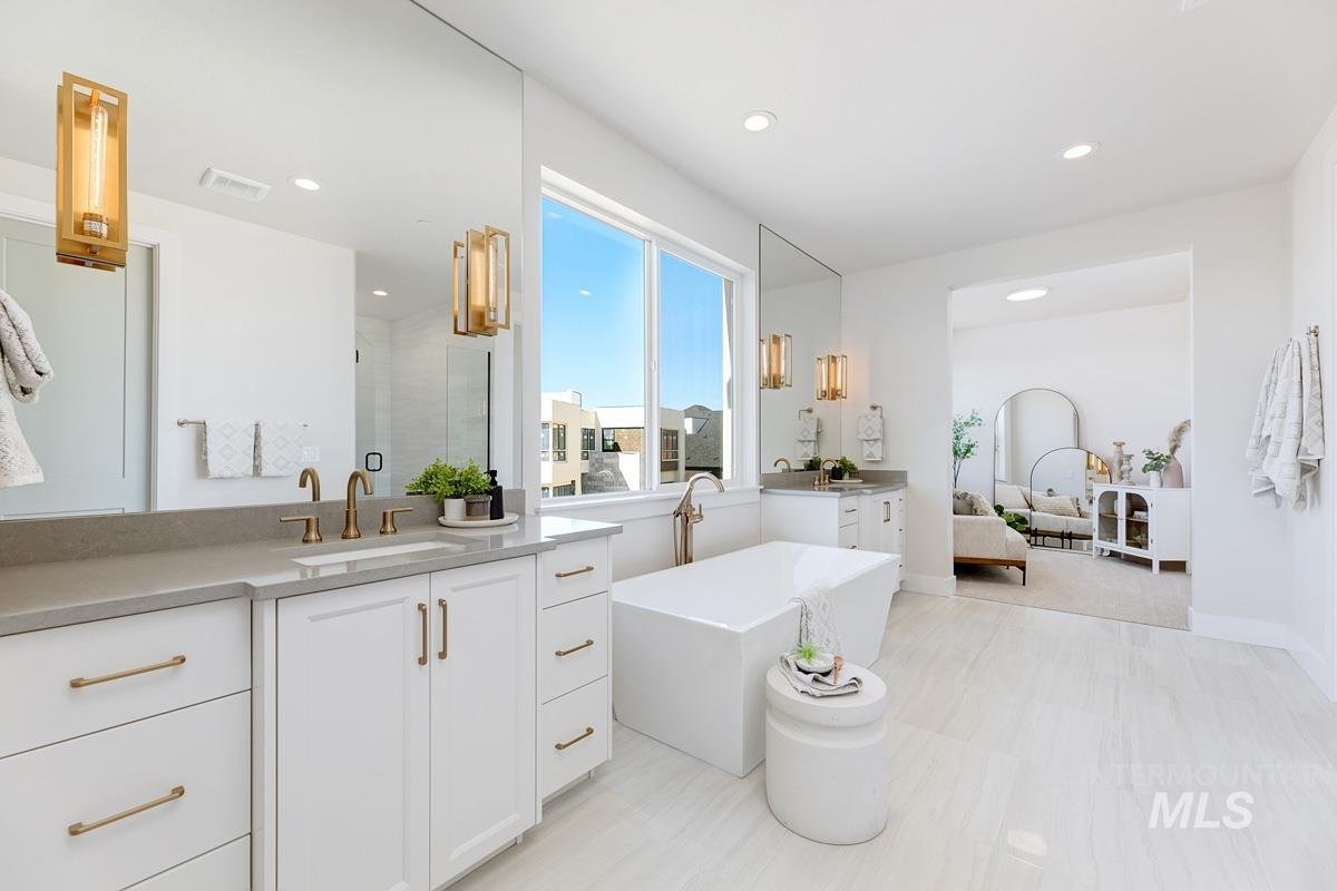 Ensuite bathroom featuring two vanities, a stall shower, recessed lighting, and a soaking tub
