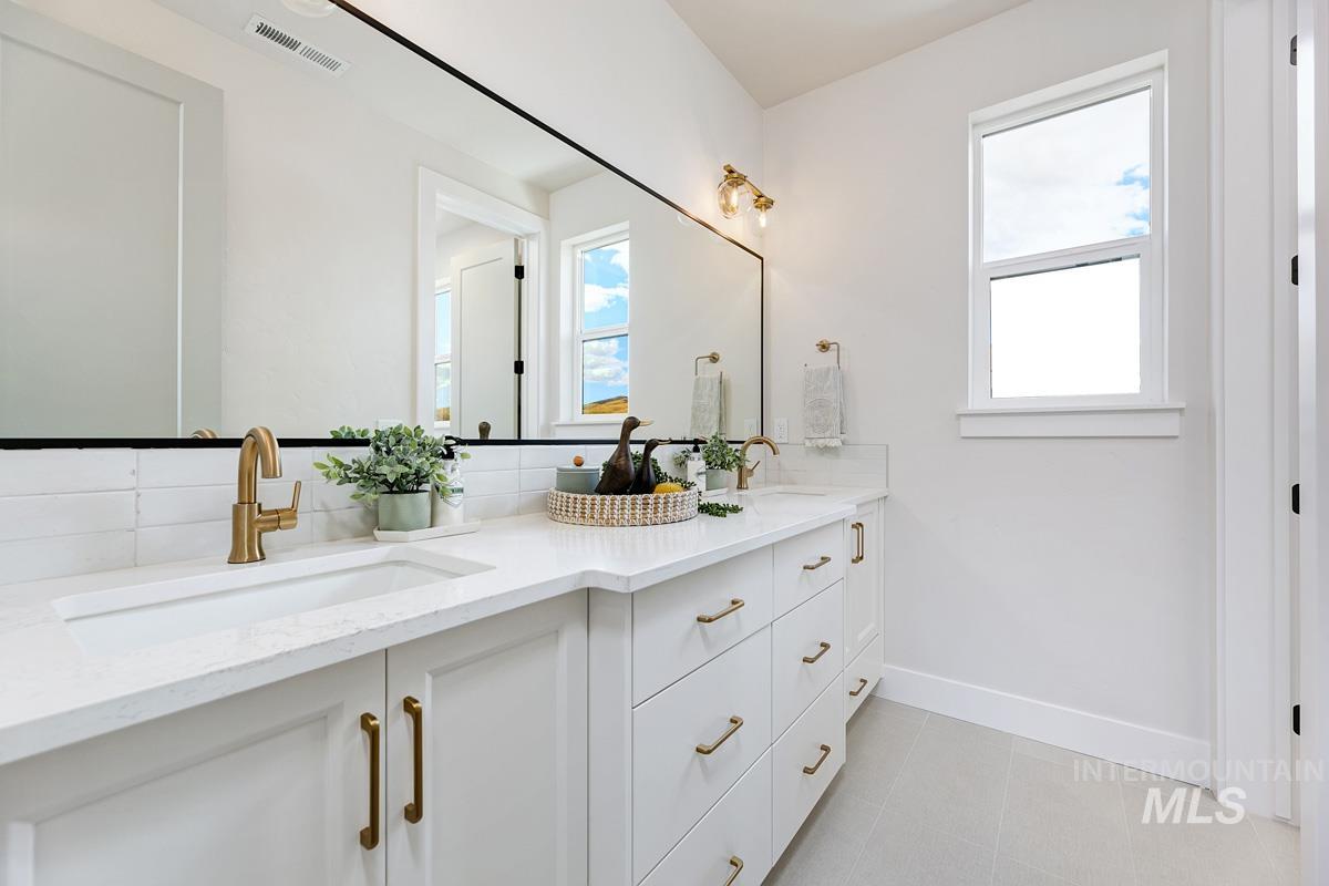 Bathroom with double vanity, backsplash, and light tile patterned floors