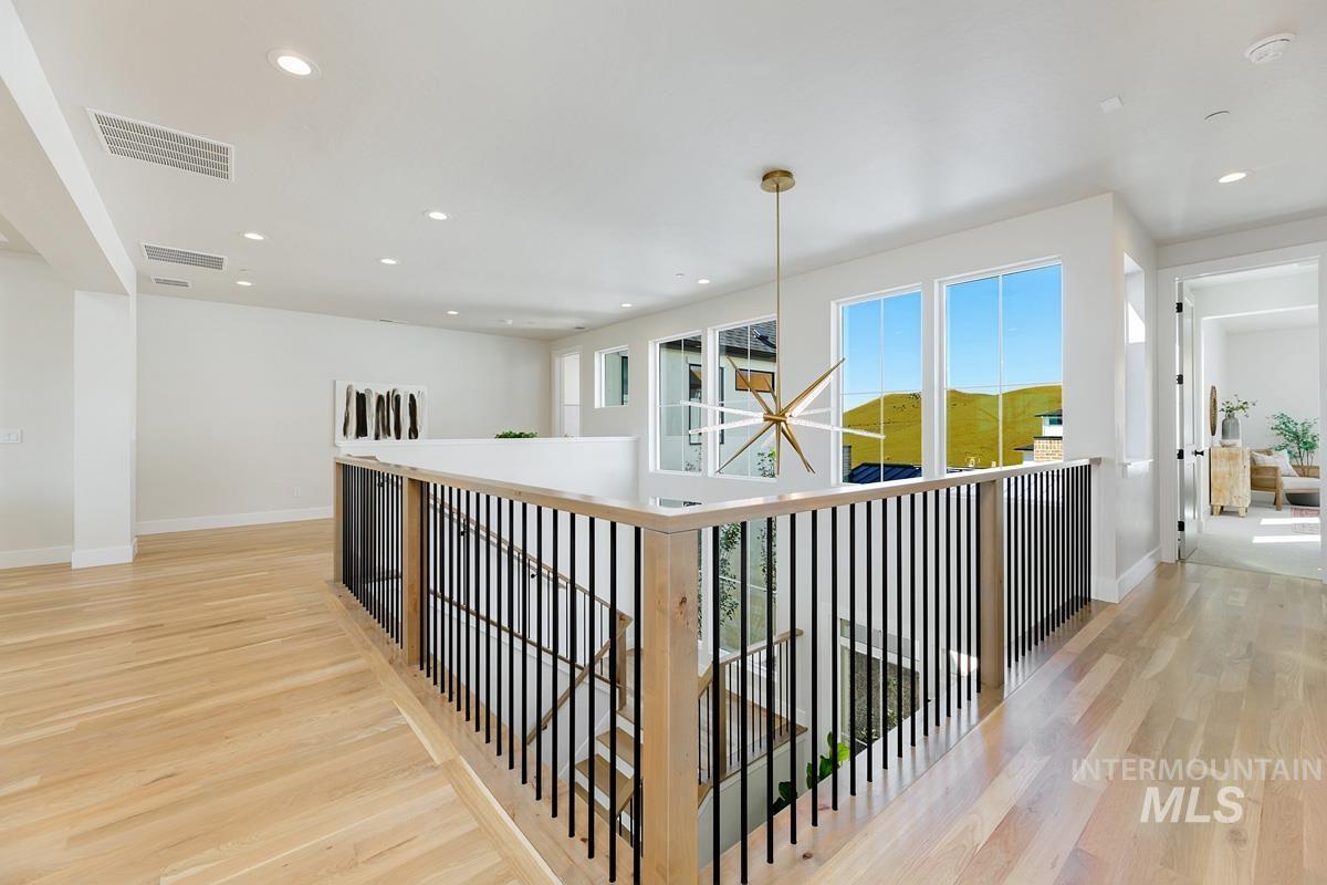 Hallway featuring light wood-style floors, recessed lighting, a chandelier, and an upstairs landing