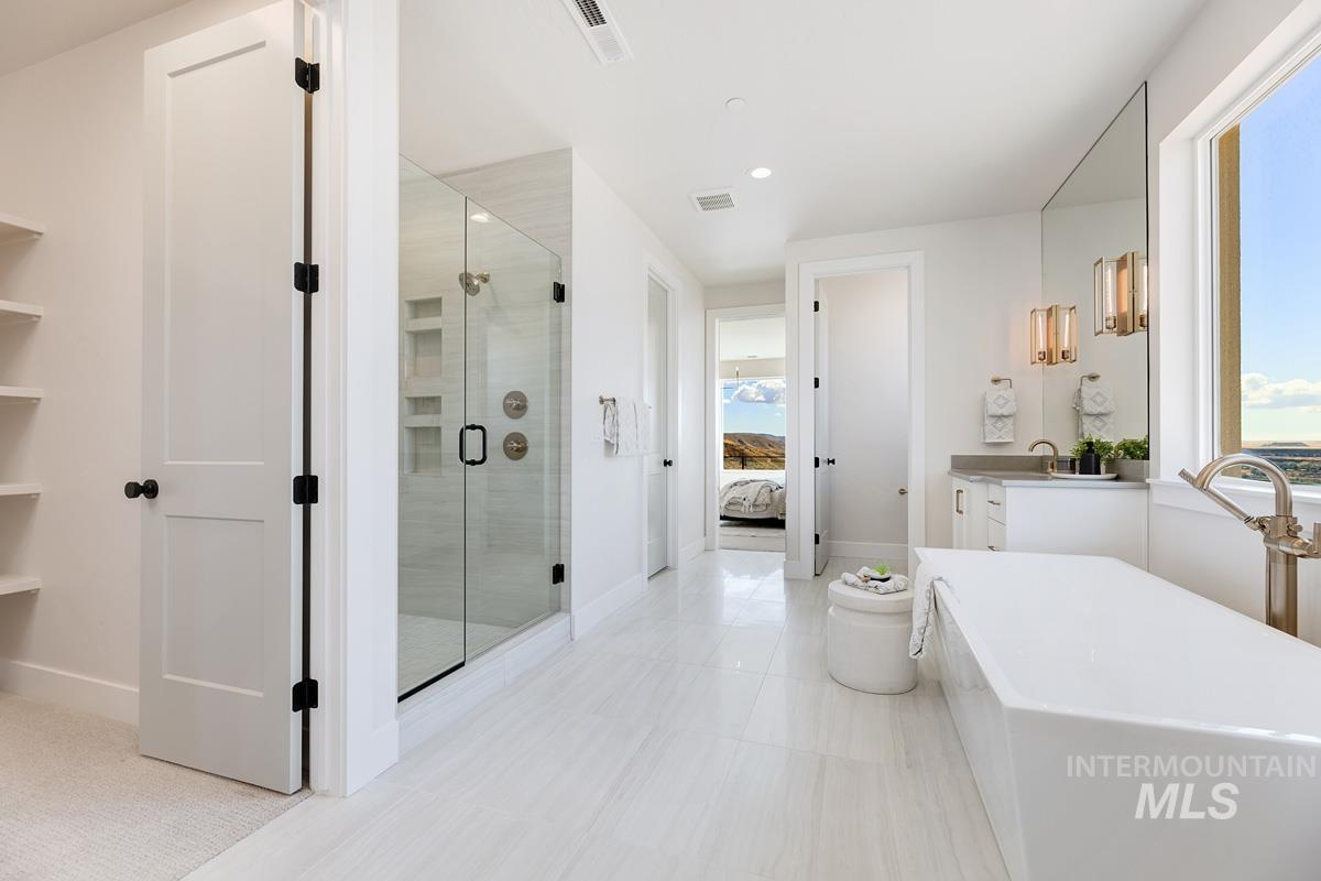 Ensuite bathroom featuring vanity, a freestanding tub, a shower stall, recessed lighting, and light tile patterned floors