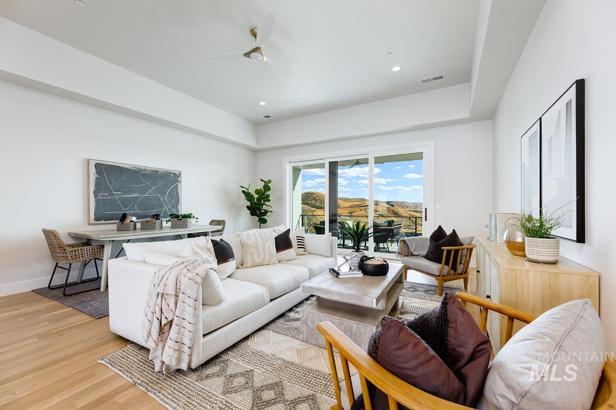 Living room featuring light wood-style floors, recessed lighting, ceiling fan, and a raised ceiling