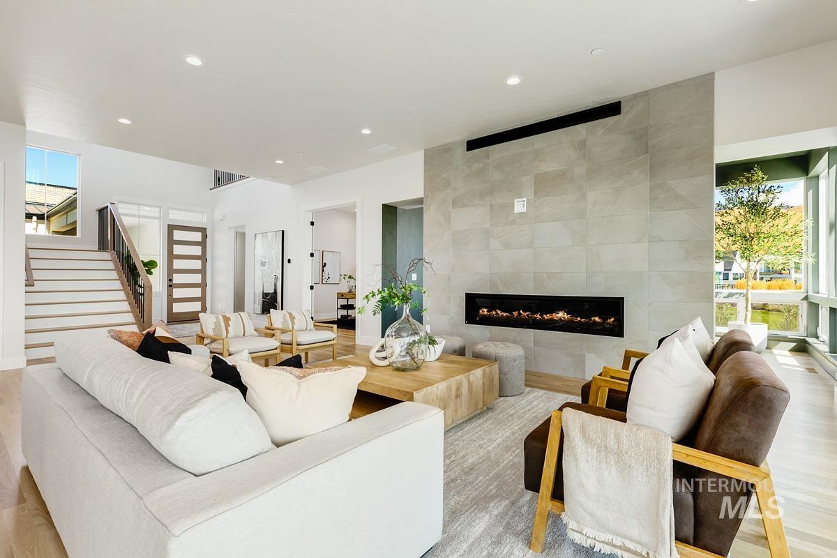 Living area featuring stairs, a fireplace, recessed lighting, light wood-style flooring, and tile walls