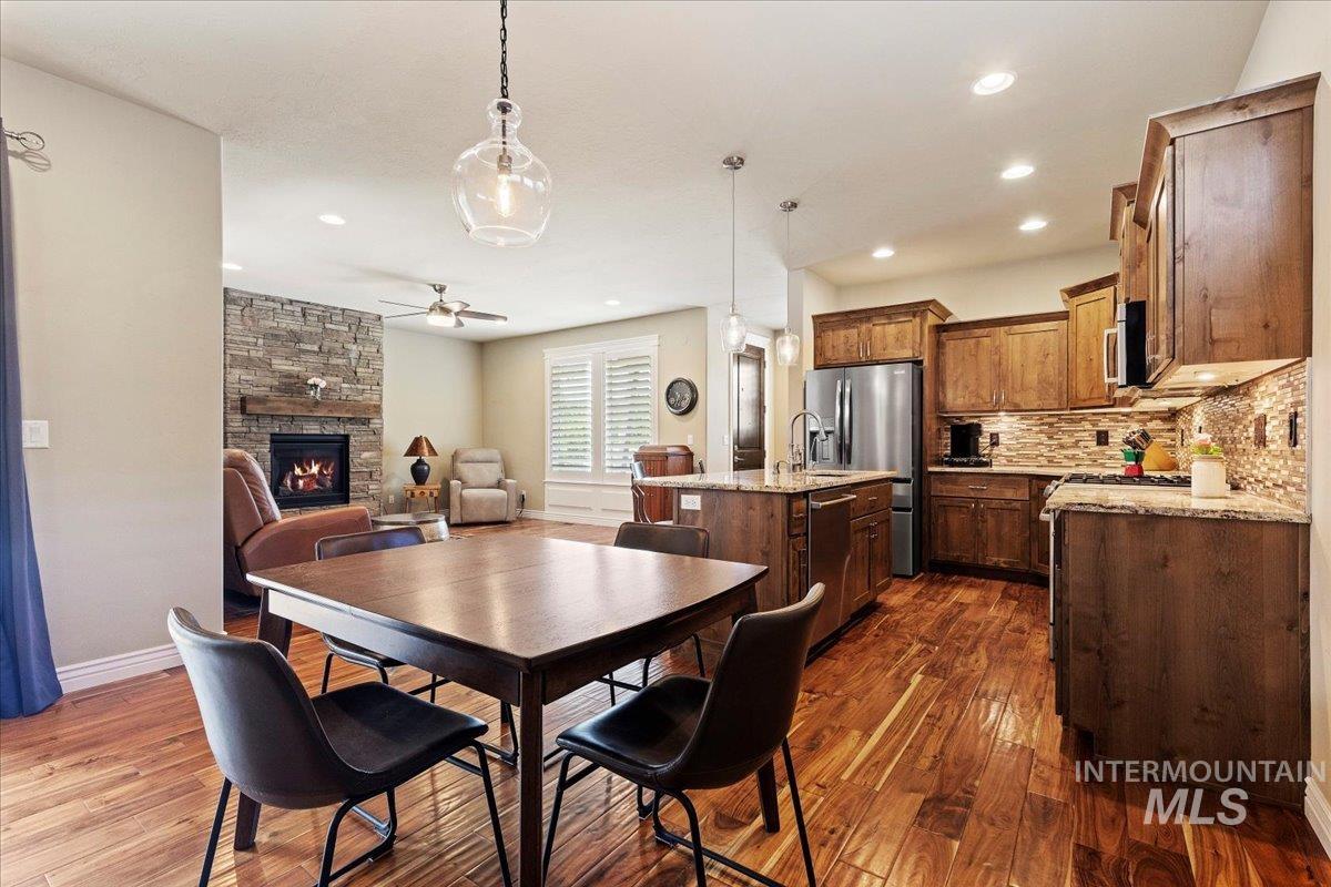 Dining area featuring ceiling fan, a fireplace, dark wood-style flooring, and recessed lighting