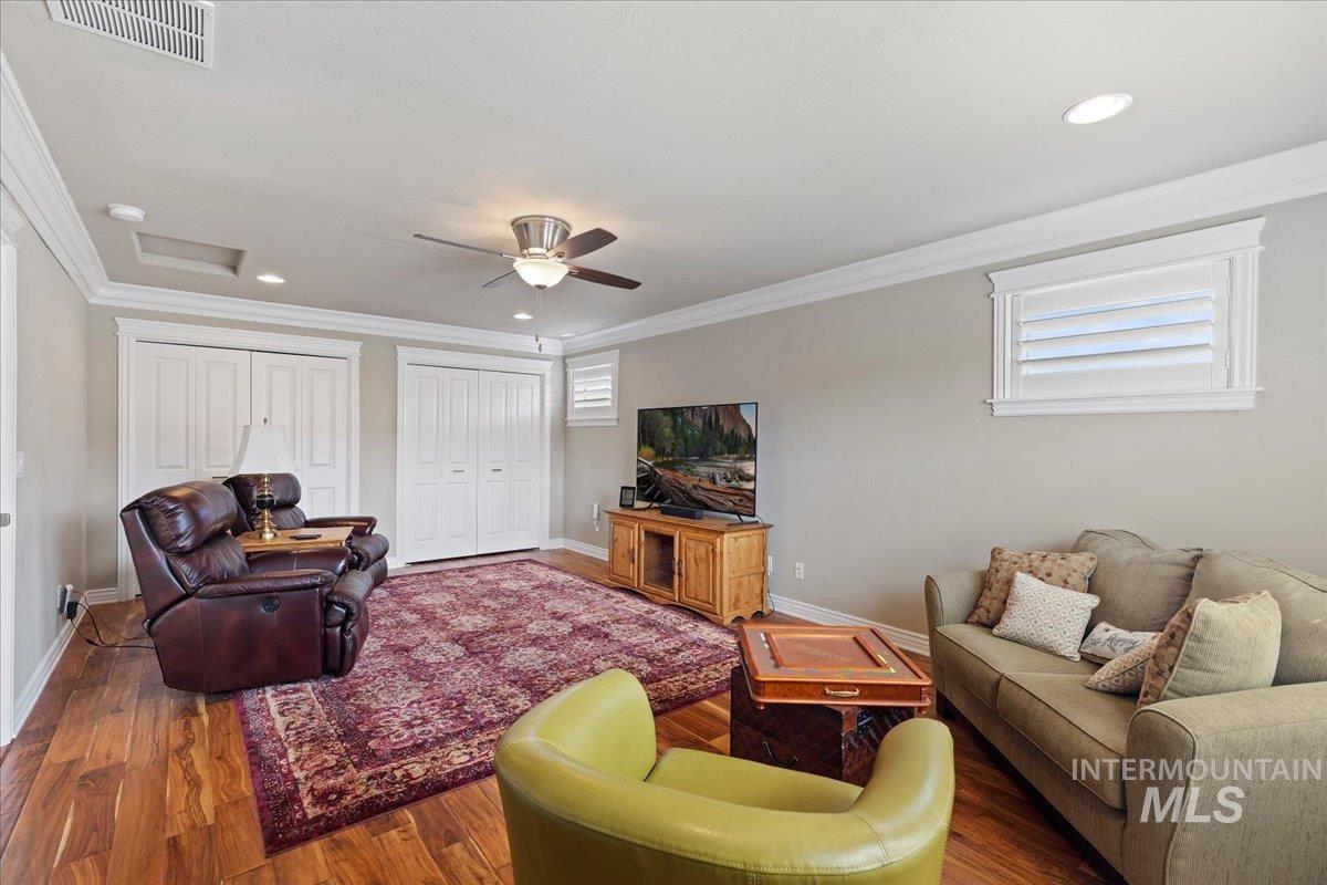 Living room featuring attic access, wood finished floors, a ceiling fan, ornamental molding, and recessed lighting