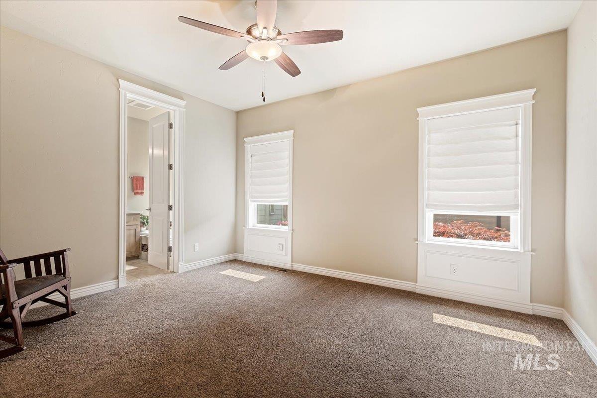 Carpeted room featuring ceiling fan and plenty of natural light