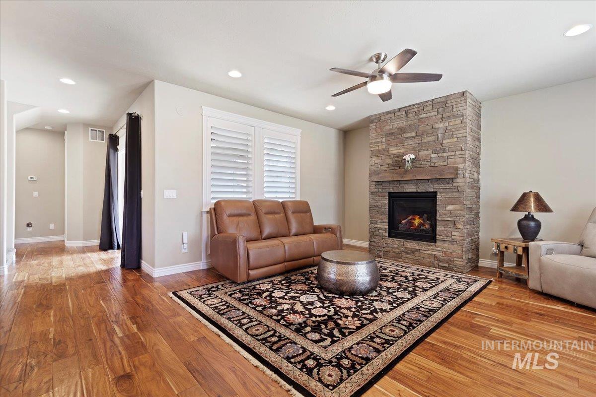 Living room featuring ceiling fan, light wood finished floors, a stone fireplace, and recessed lighting