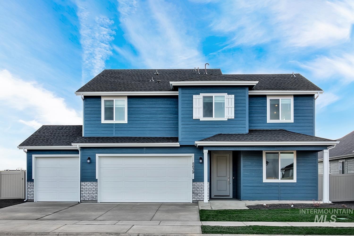 Traditional home featuring concrete driveway, roof with shingles, and a garage