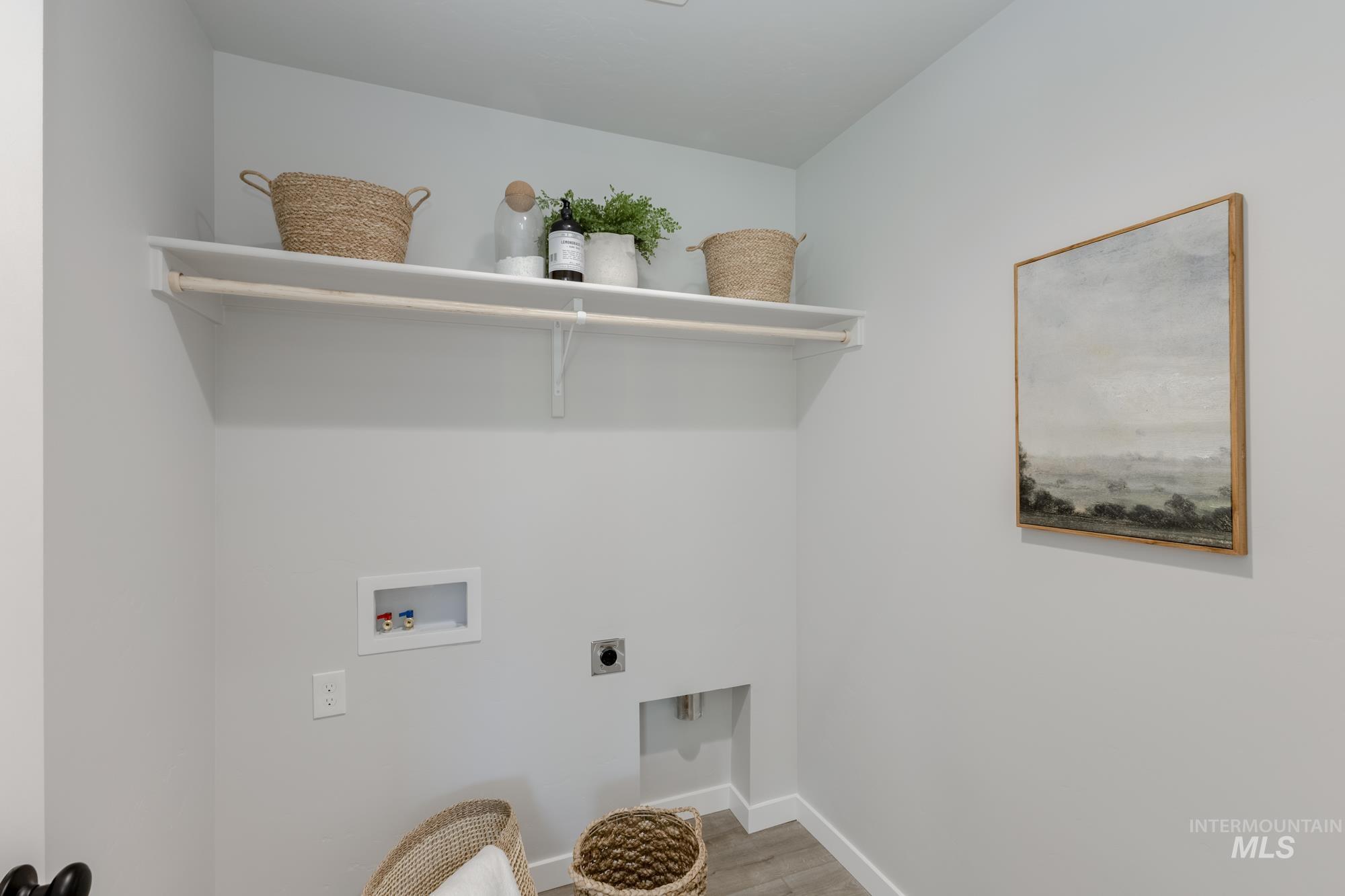 Washroom with hookup for an electric dryer, light wood-type flooring, and washer hookup