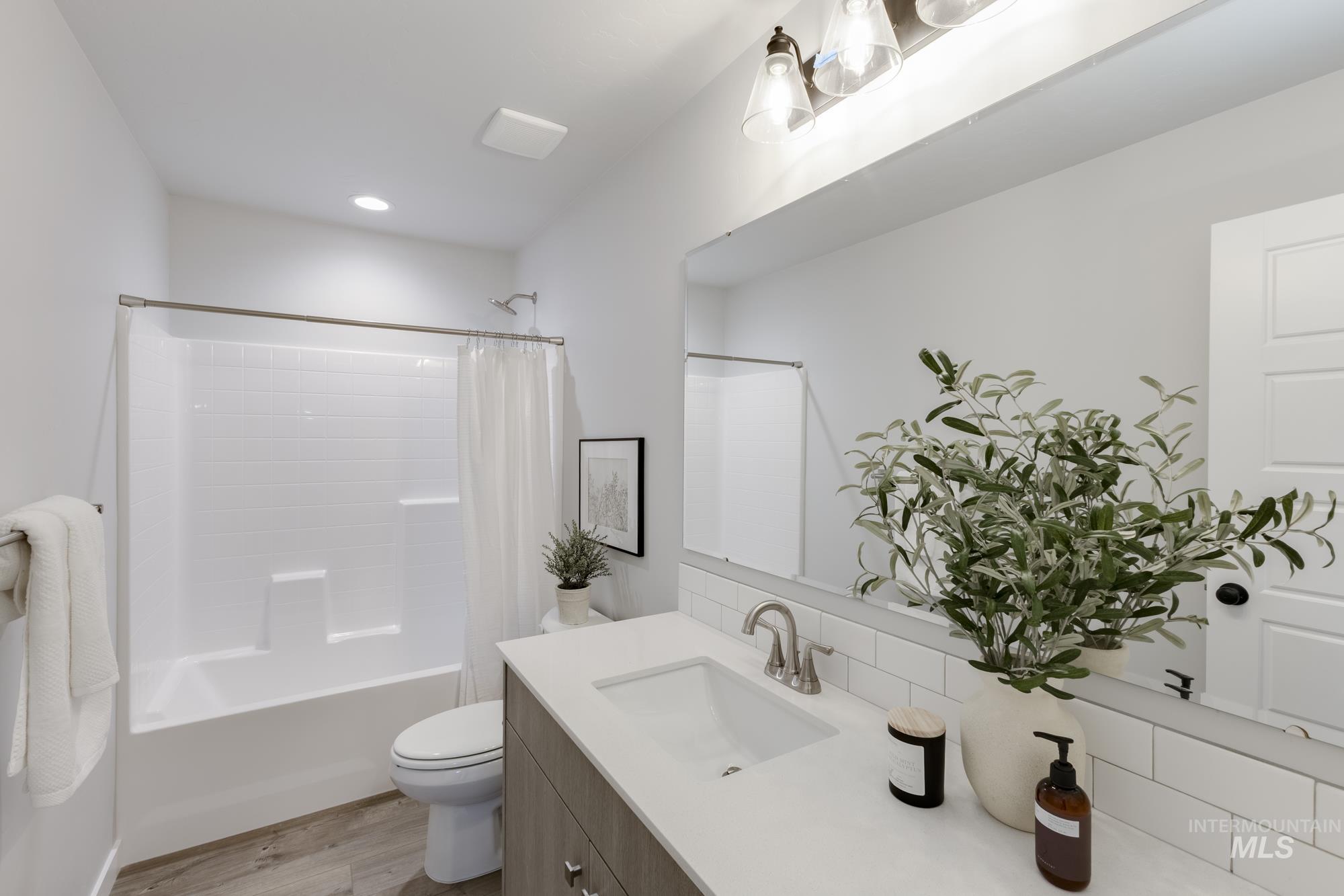 Bathroom with shower / bath combo with shower curtain, vanity, light wood-style floors, backsplash, and recessed lighting